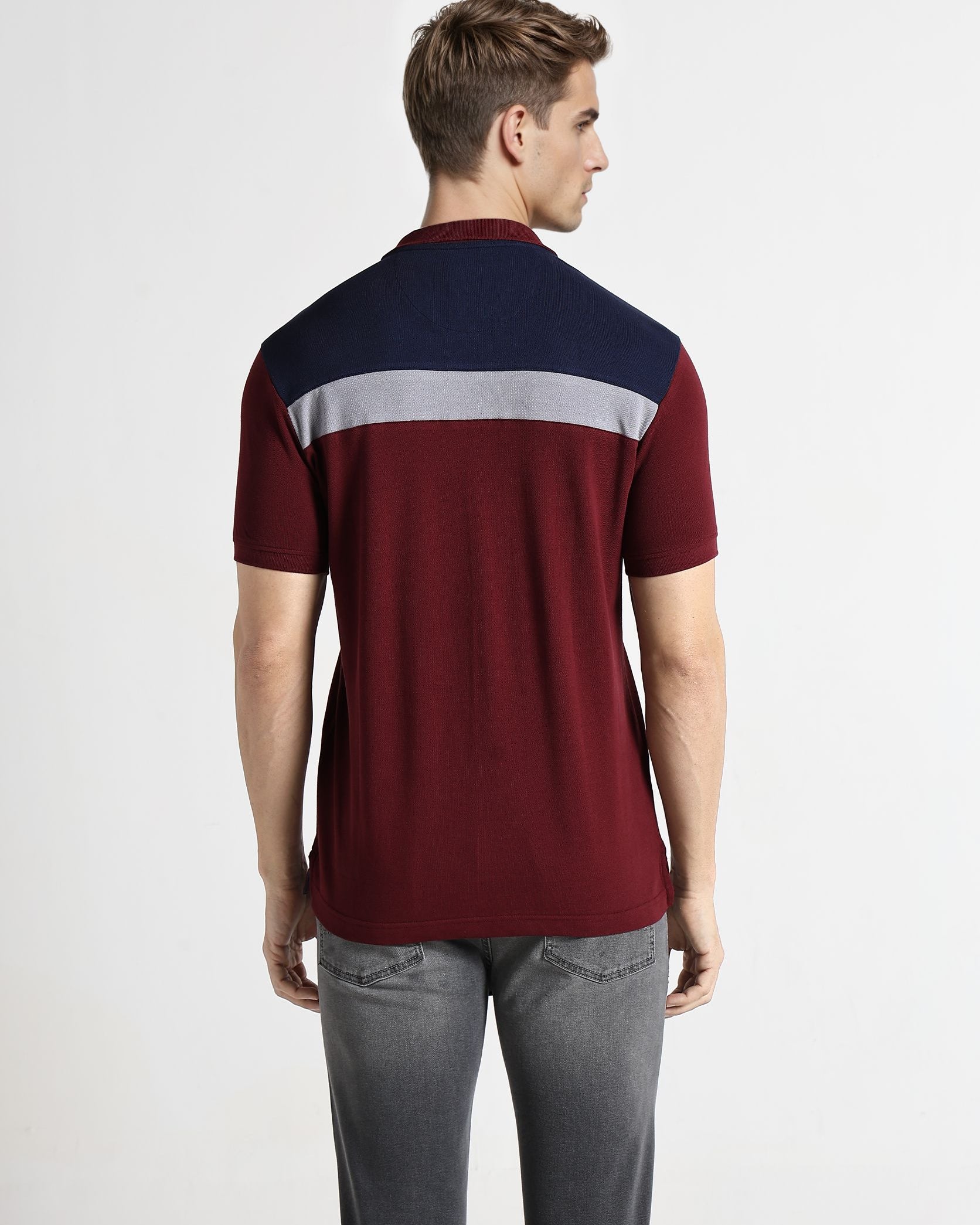 Man wearing a maroon and navy color-blocked shirt on a white background