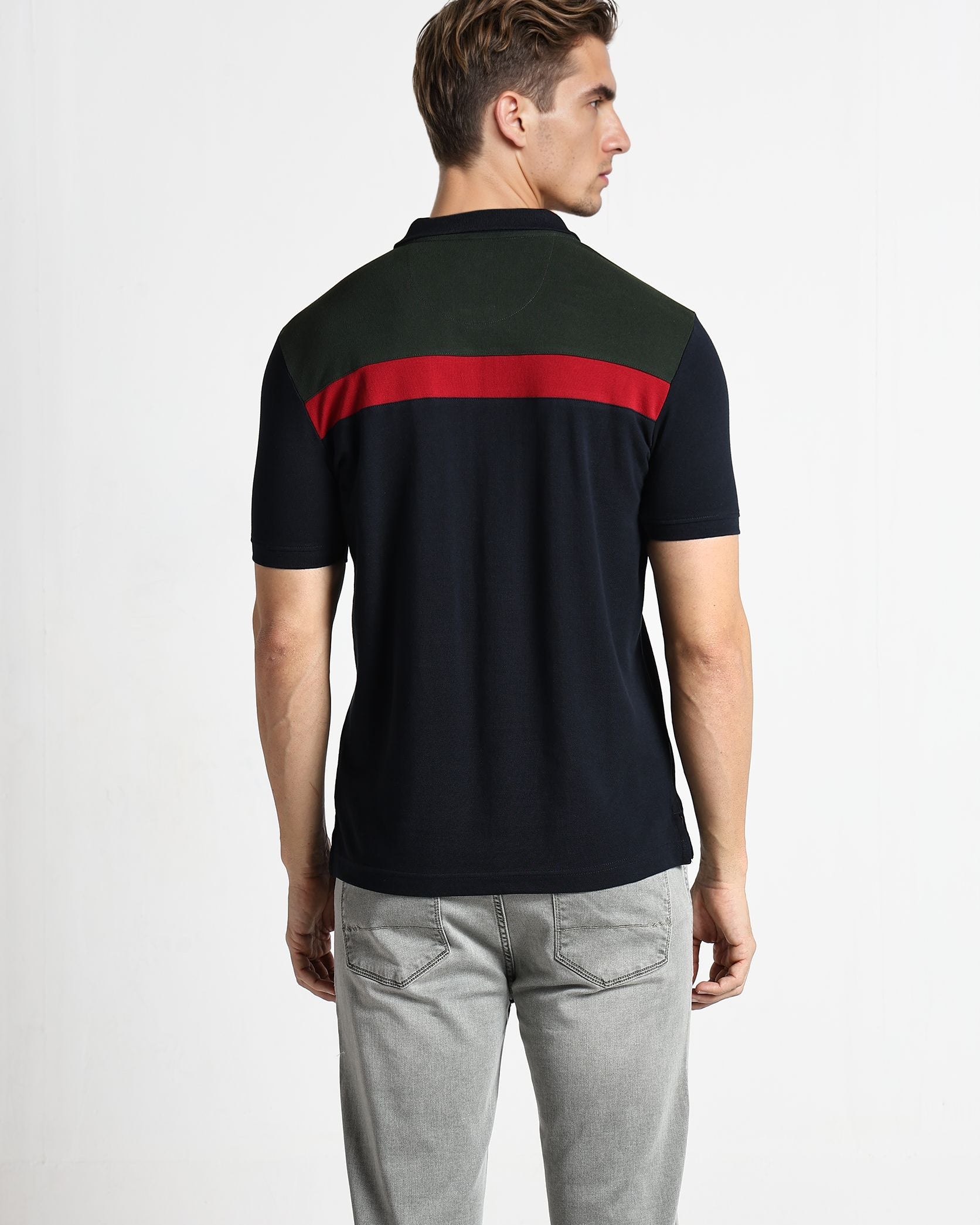 Man wearing a black polo shirt with a red stripe on a white background