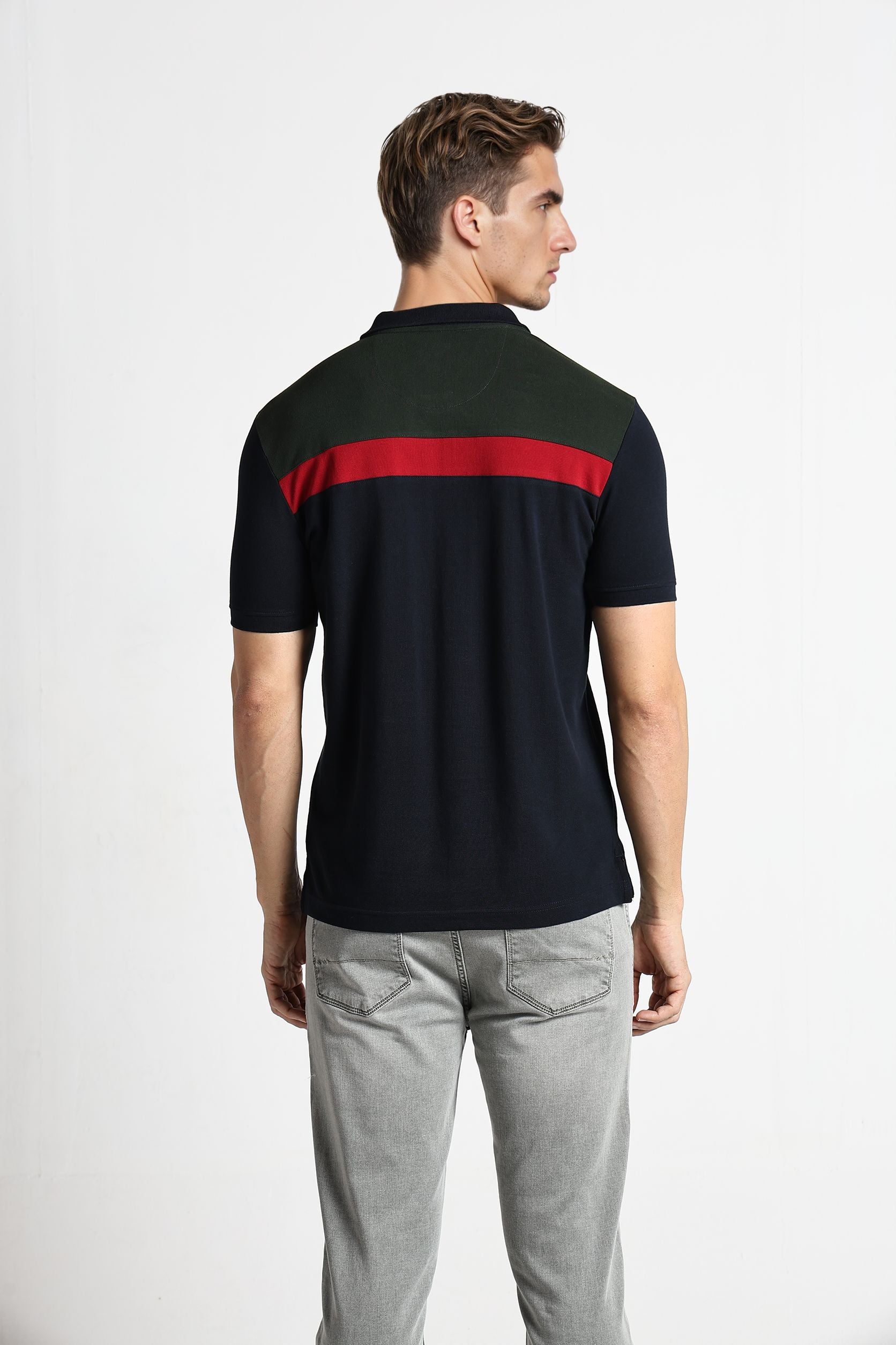 Man wearing a black polo shirt with a red stripe on a white background