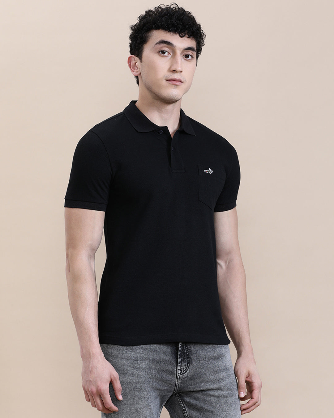Man wearing a black casual solid black polo t shirt with pocket with casual styling on a gray background