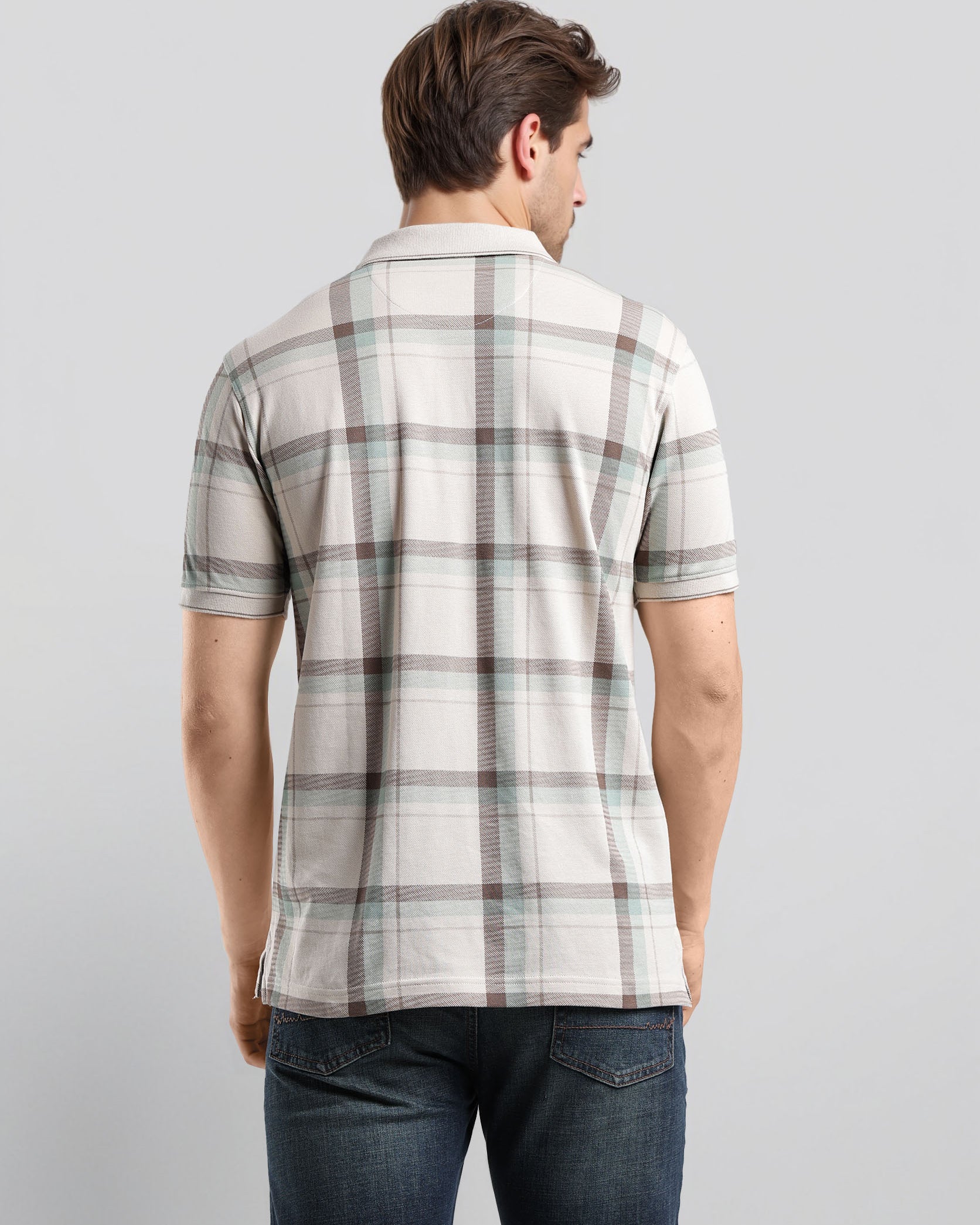 Man wearing a plaid shirt and jeans on a light gray background