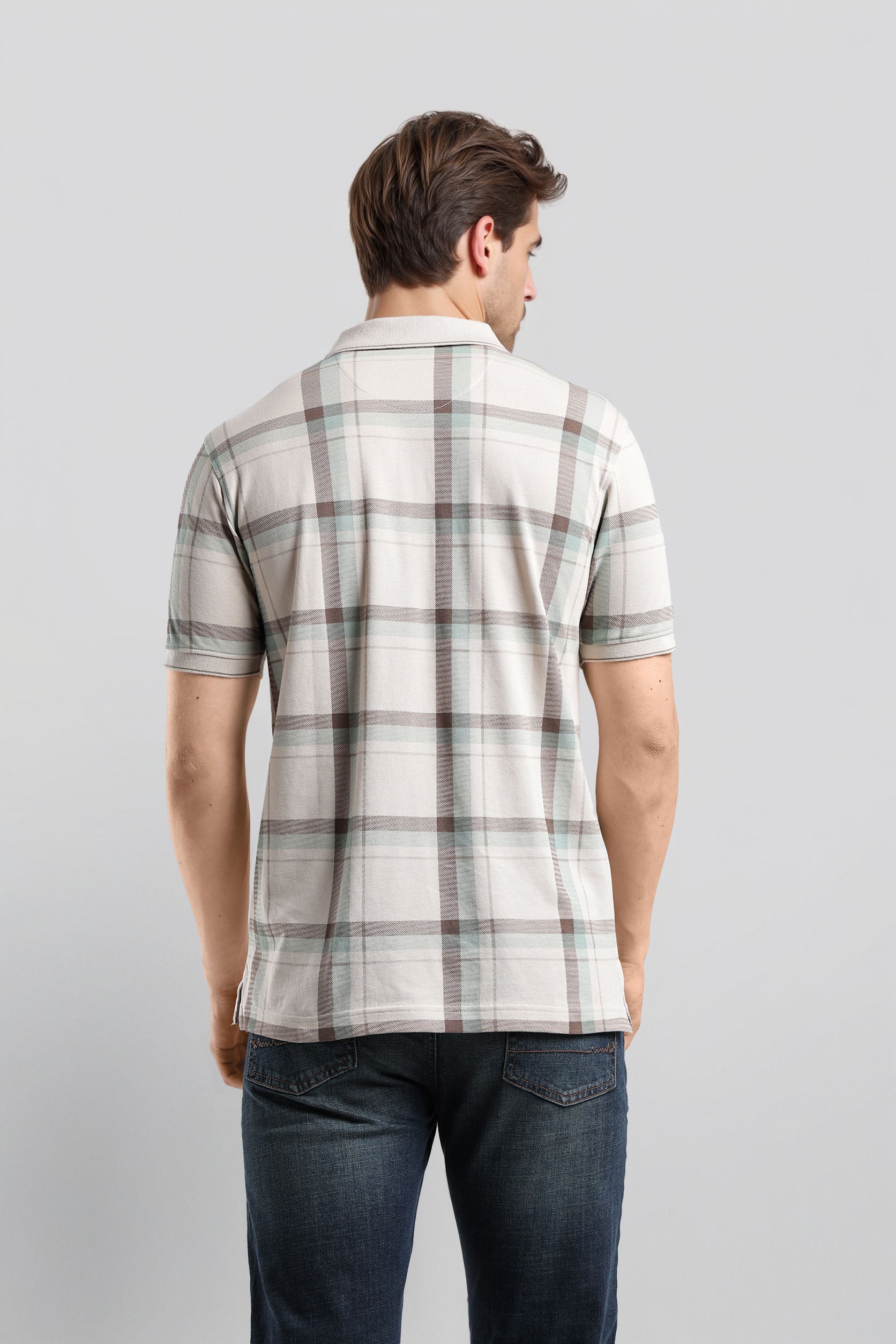 Man wearing a plaid shirt and jeans on a light gray background