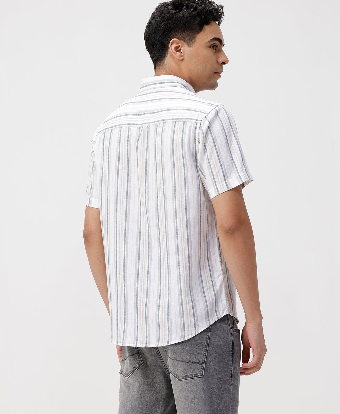 Man wearing a white white and green stripes comfort fit casuals shirts on a light gray background