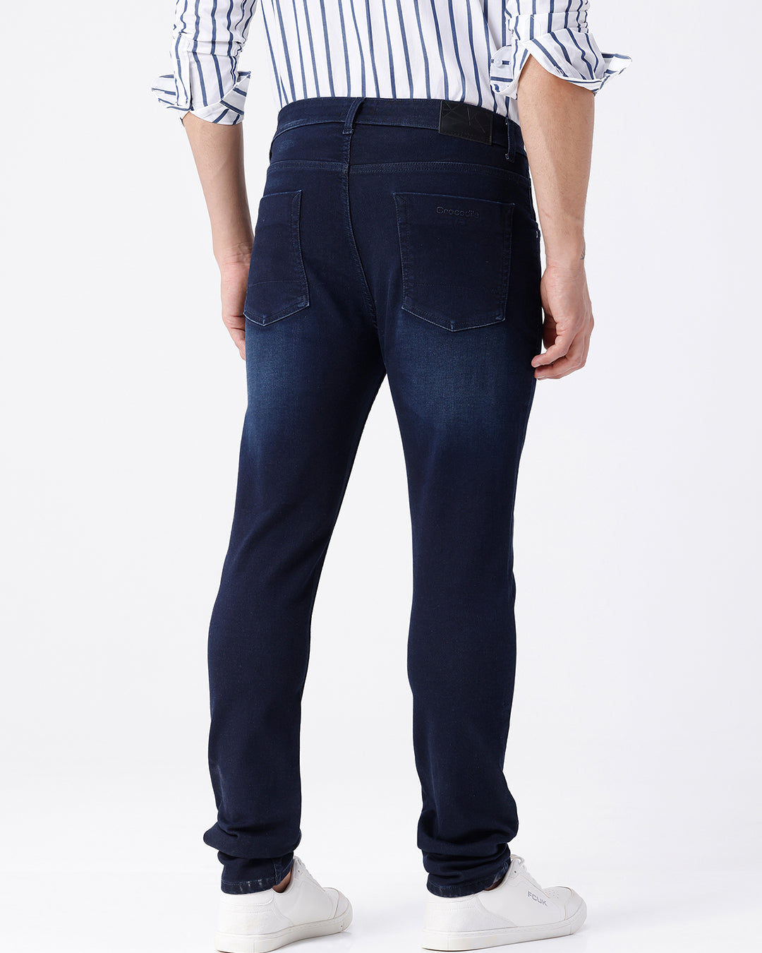 Man wearing a blue dark blue knit slim fit jeans with casual styling on a gray background
