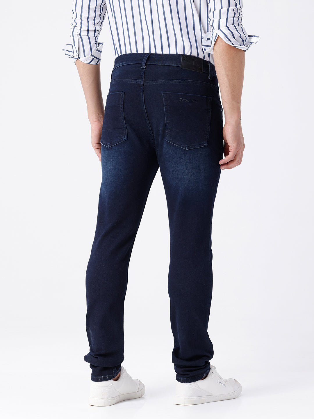 Man wearing a blue dark blue knit slim fit jeans with casual styling on a gray background