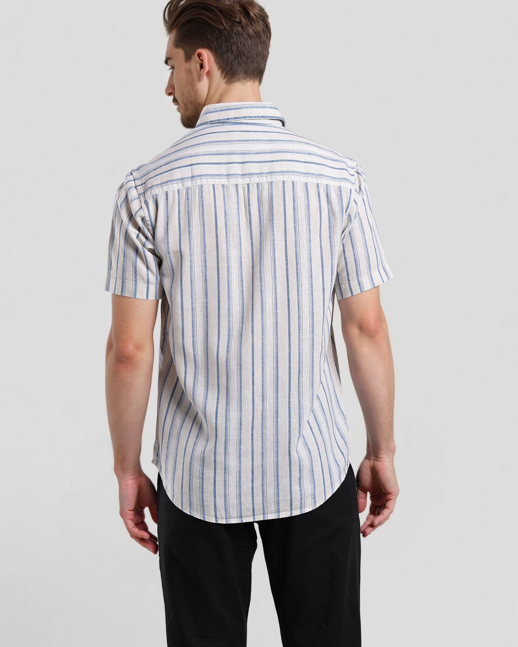 Man wearing a striped shirt and black pants on a light gray background