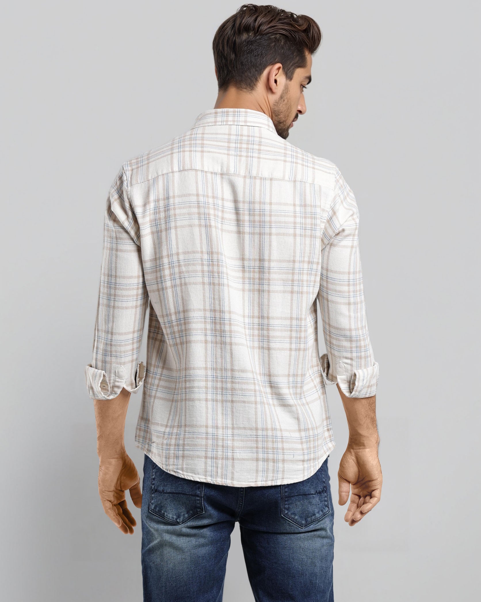 Man wearing a white checkered shirt and blue jeans on a gray background