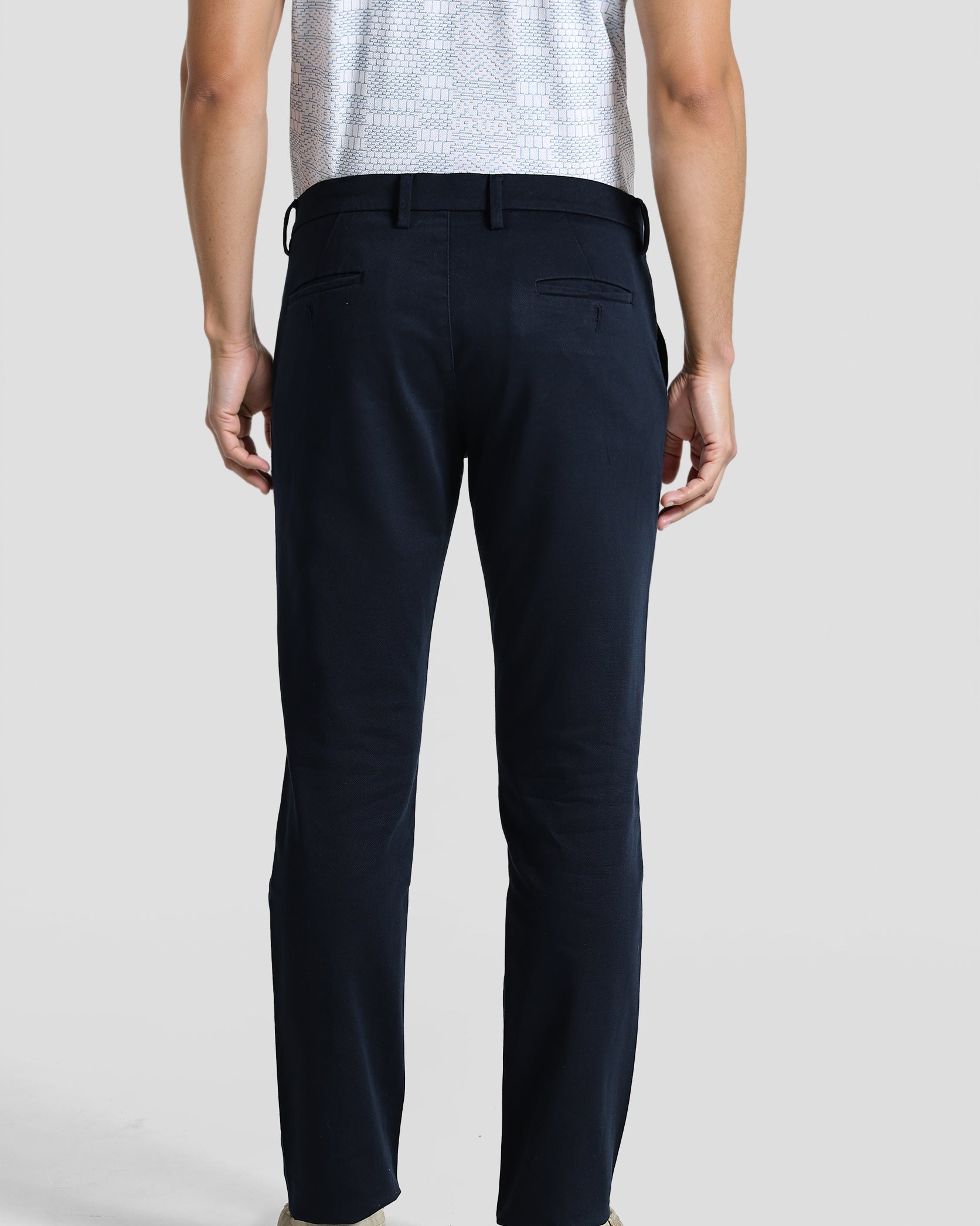 Person wearing navy pants and a light-colored shirt on a plain background