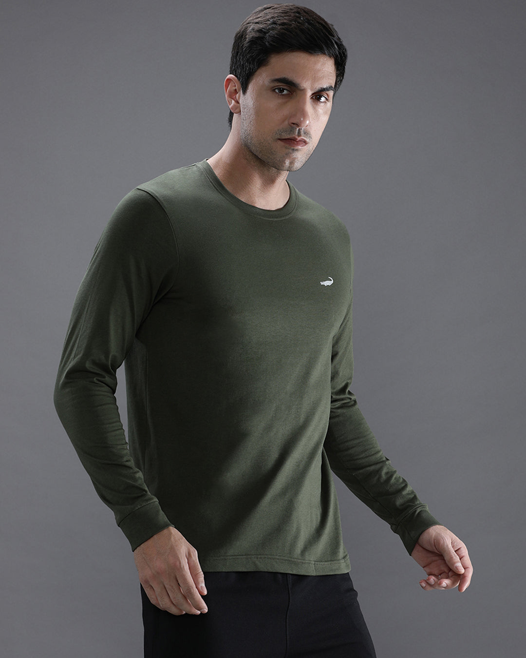 Man wearing a green solid green sport fit t shirt with casual styling on a gray background