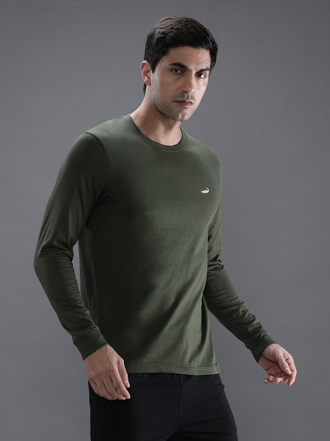 Man wearing a green solid green sport fit t shirt with casual styling on a gray background