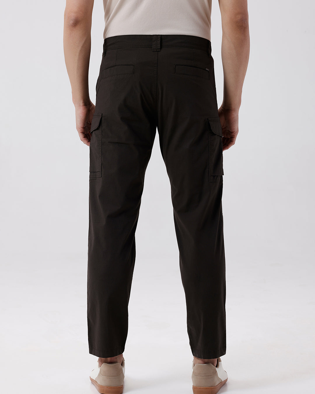 Man wearing a grey utility trekflex cargo pant in dark grey on a light gray background