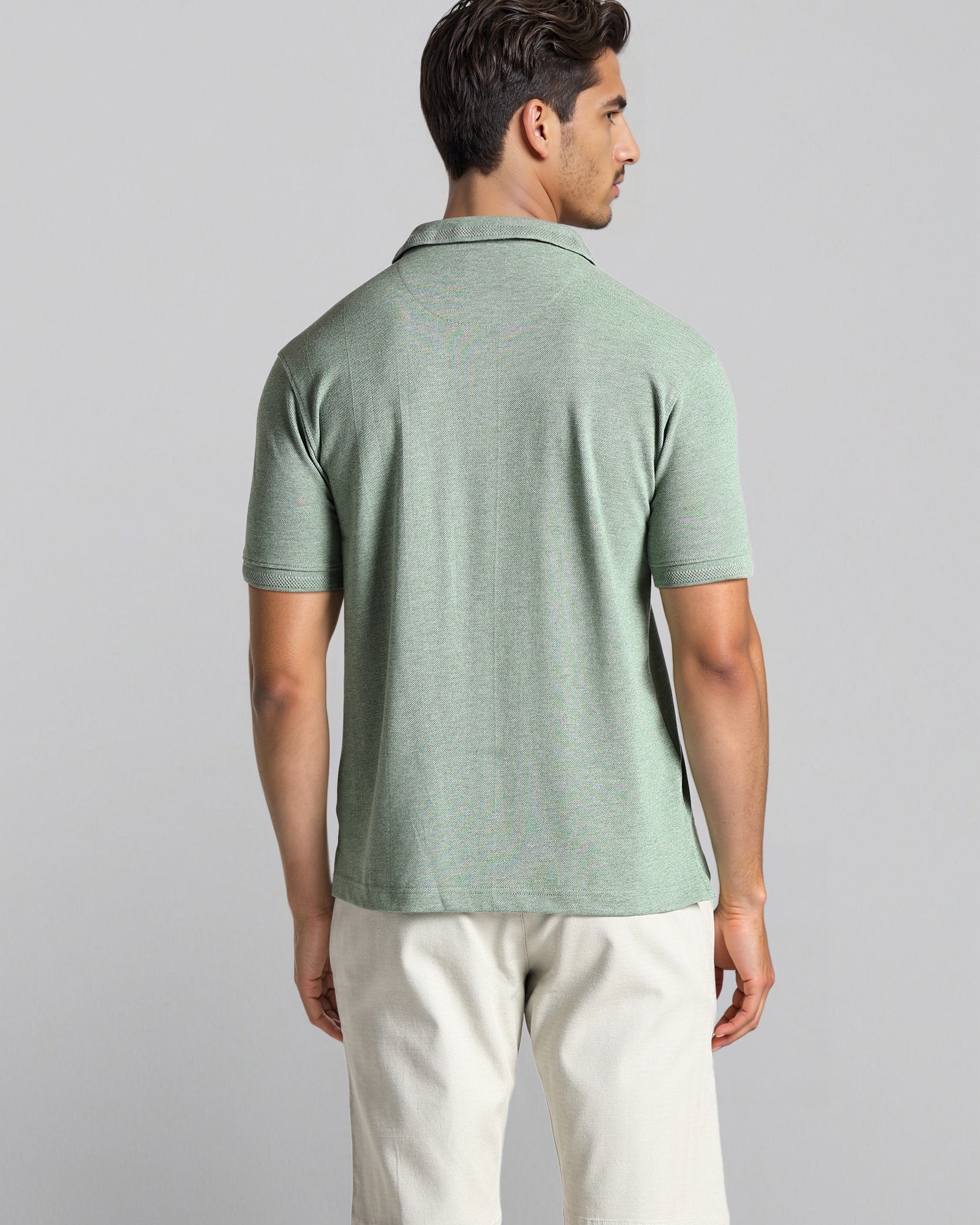 Man wearing a green polo shirt and white shorts on a gray background