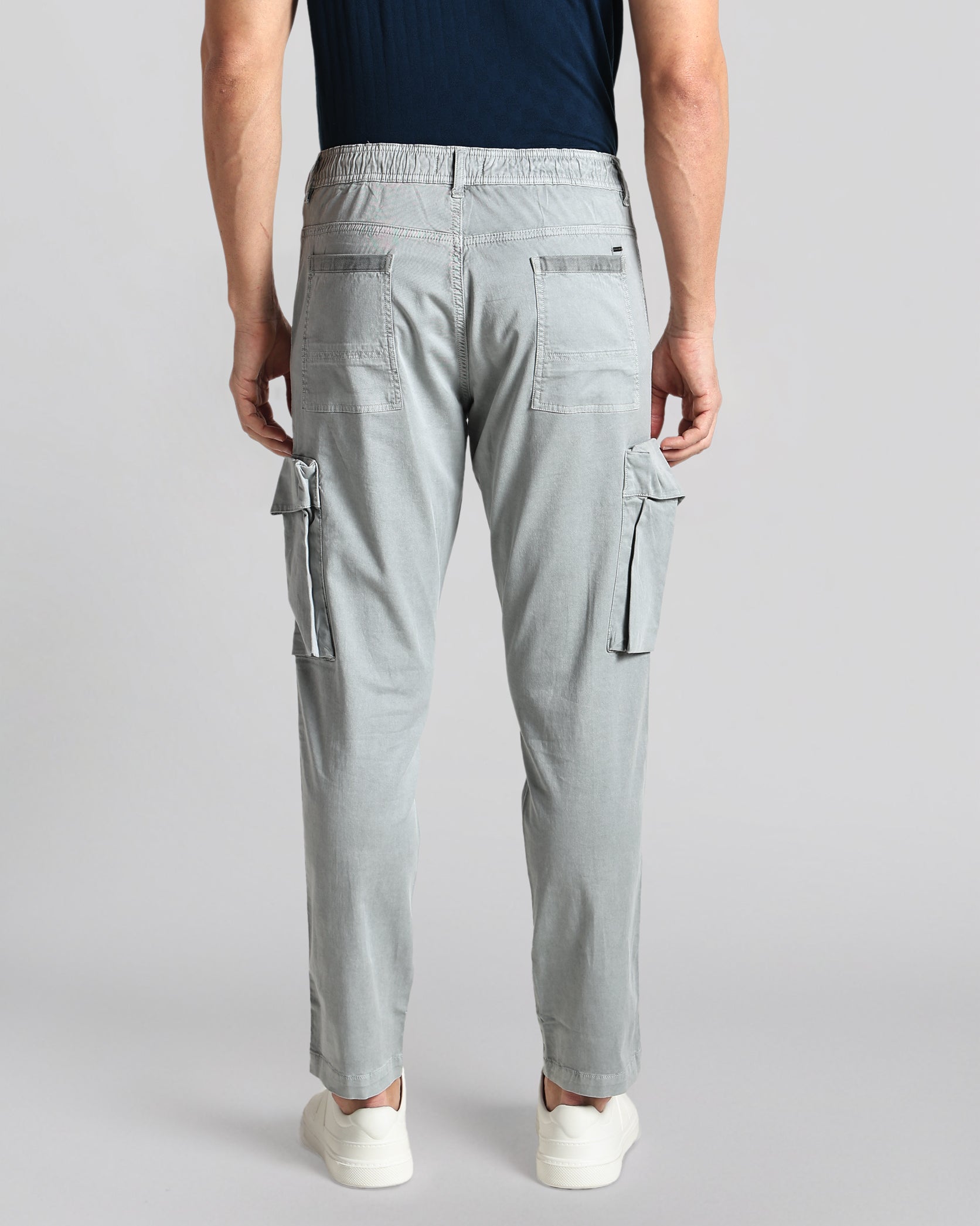 Person wearing light gray cargo pants on a plain background