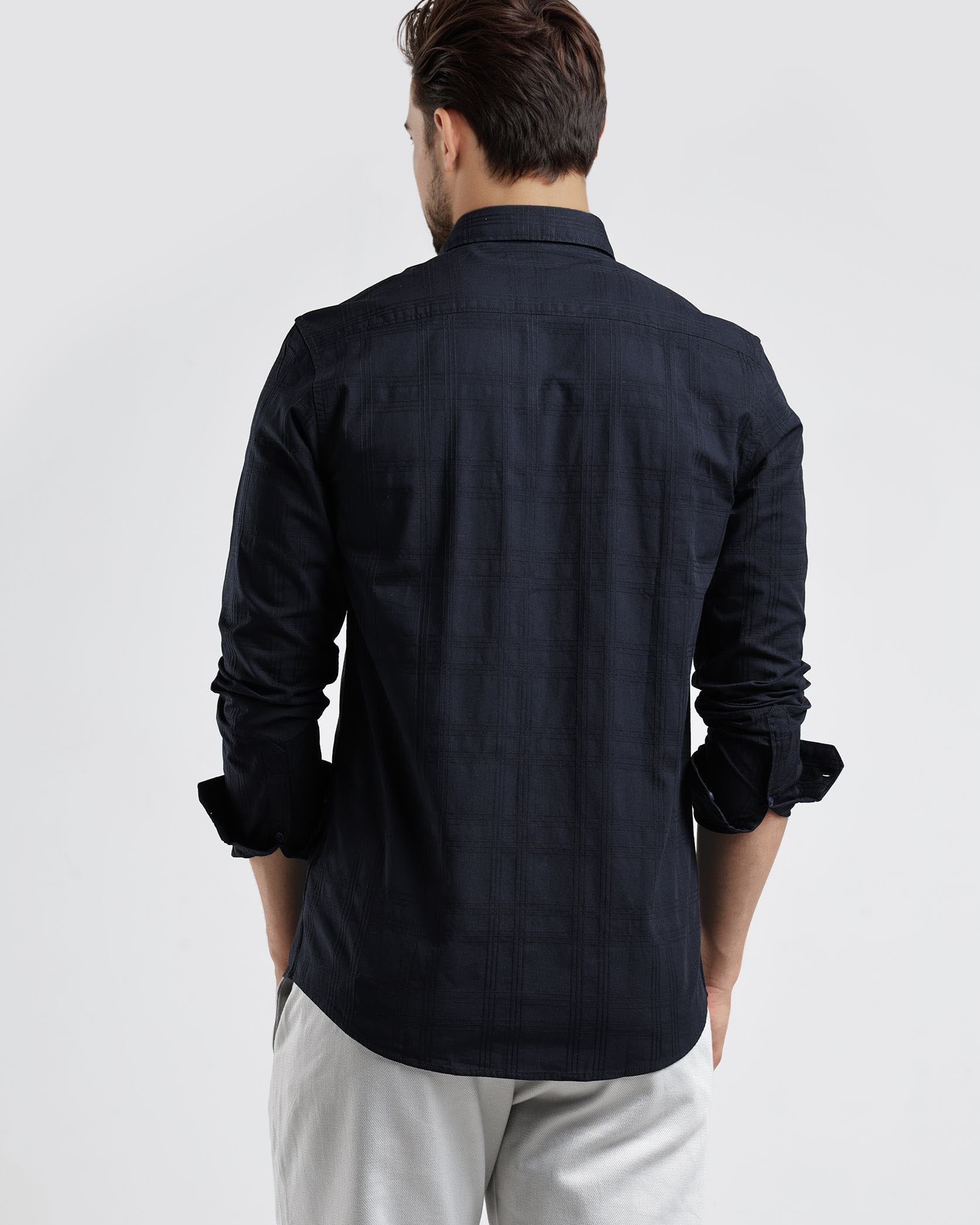 Man wearing a black shirt and light gray pants on a white background