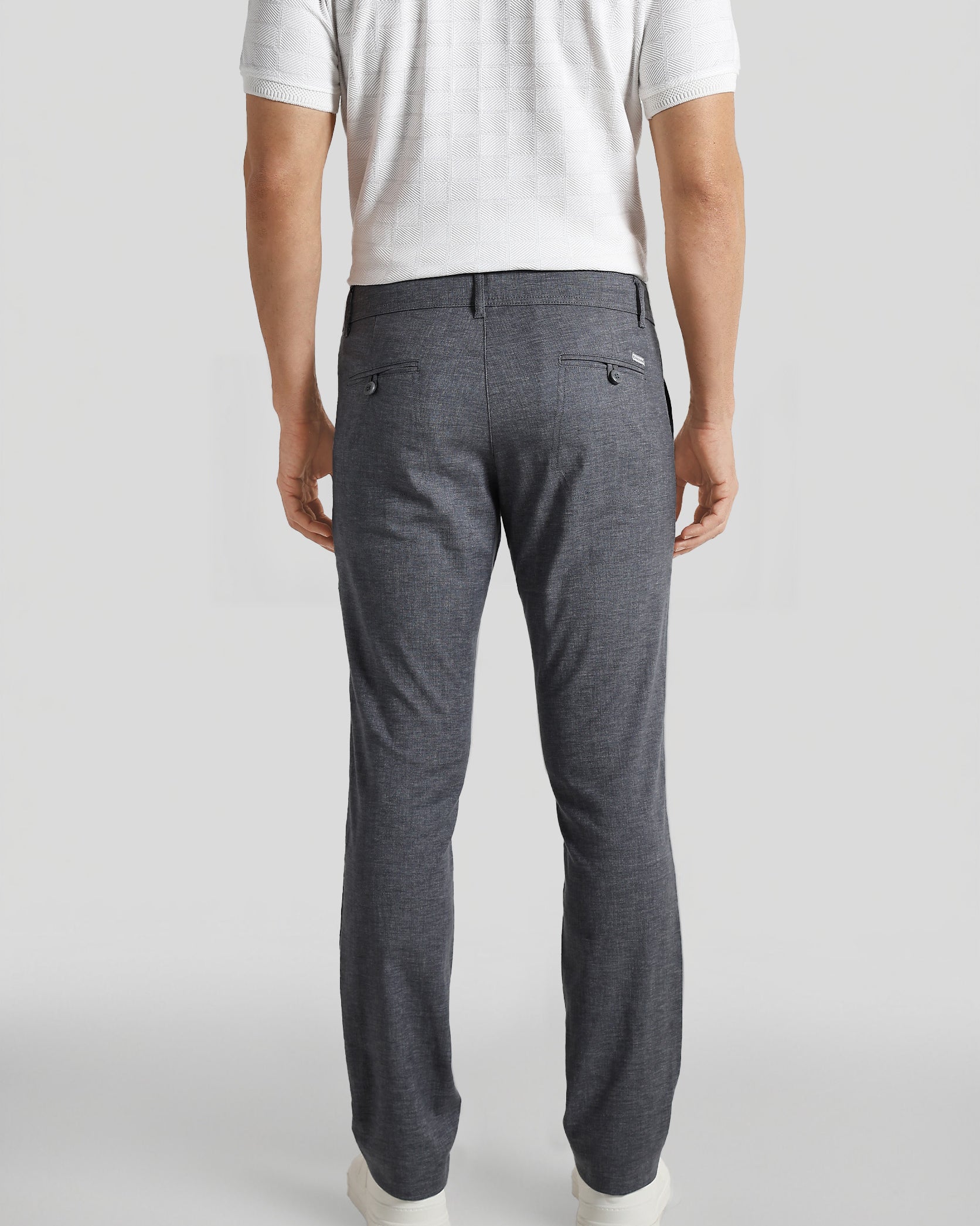 Person wearing gray pants and a white shirt on a plain background