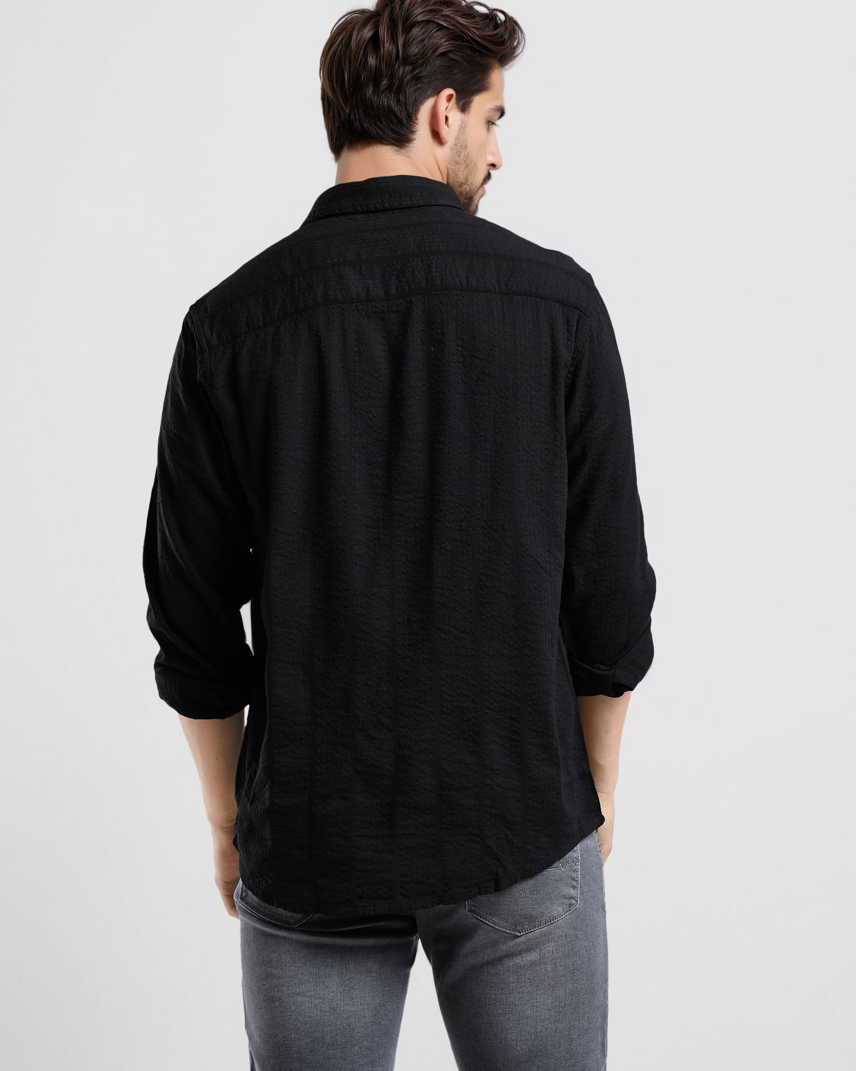 Man wearing a black shirt and gray pants on a white background