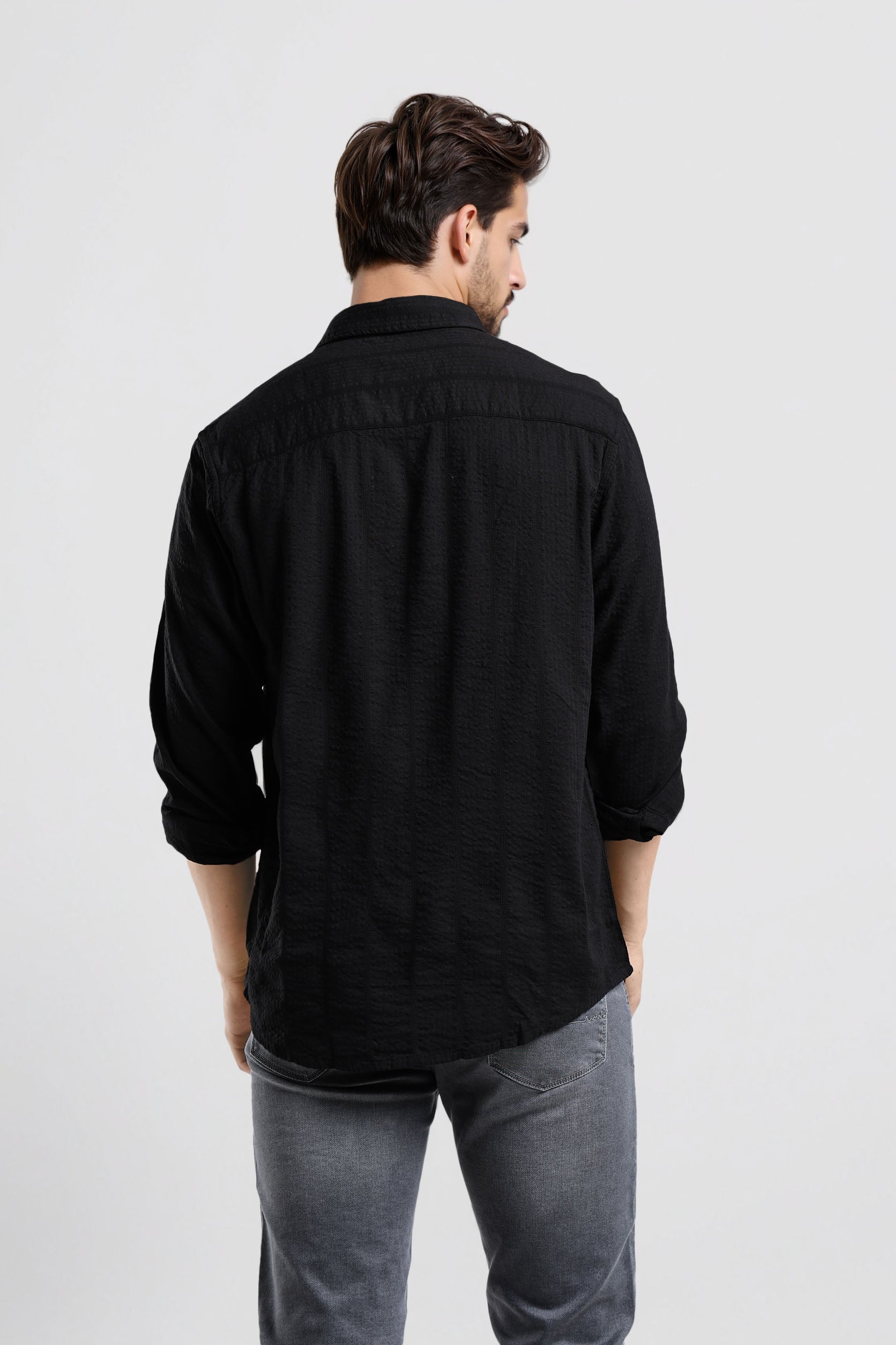 Man wearing a black shirt and gray pants on a white background