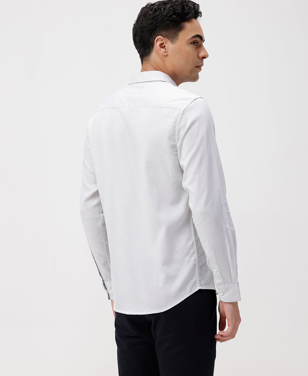 Man wearing a white white all over print slim fit casuals shirts with casual styling on a gray background