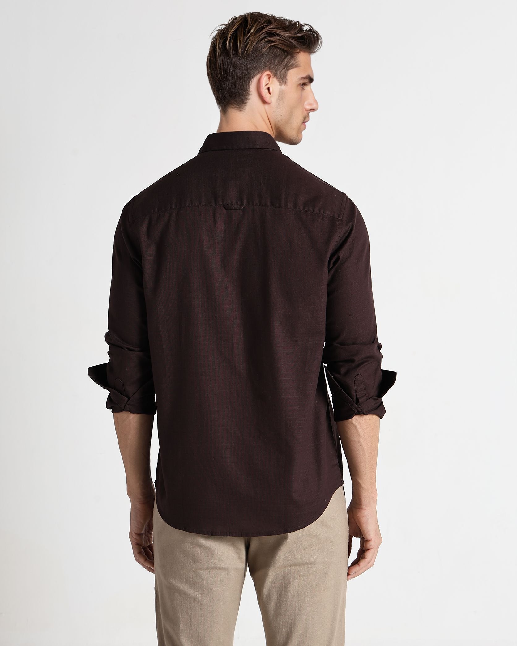 Man wearing a brown shirt and beige pants on a white background