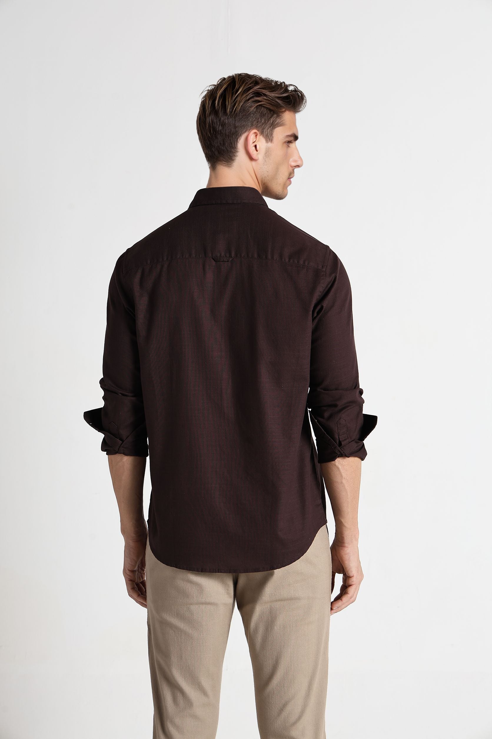 Man wearing a brown shirt and beige pants on a white background