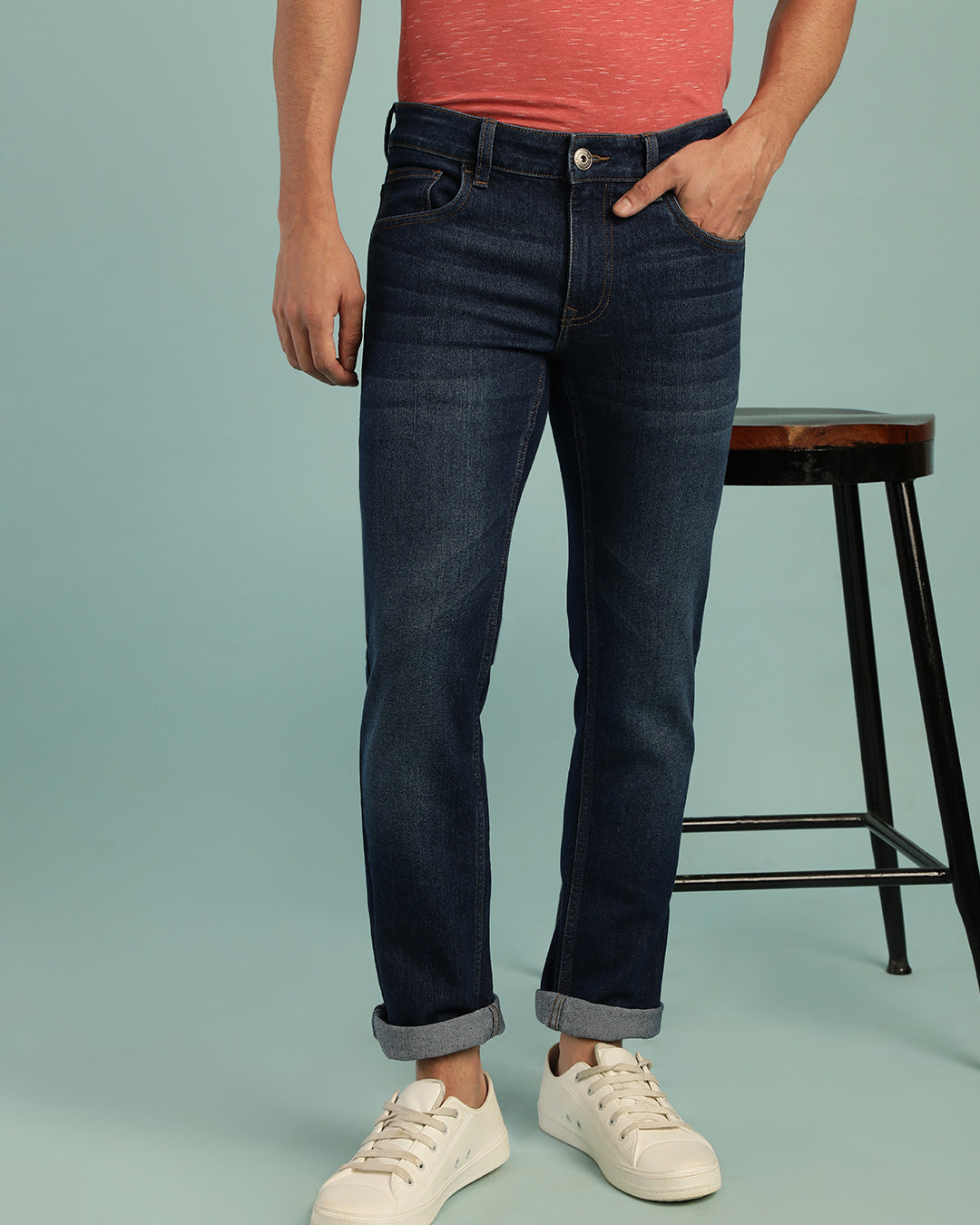 Man wearing a blue mid blue casual solid mid rise slim fit jean on a light gray background