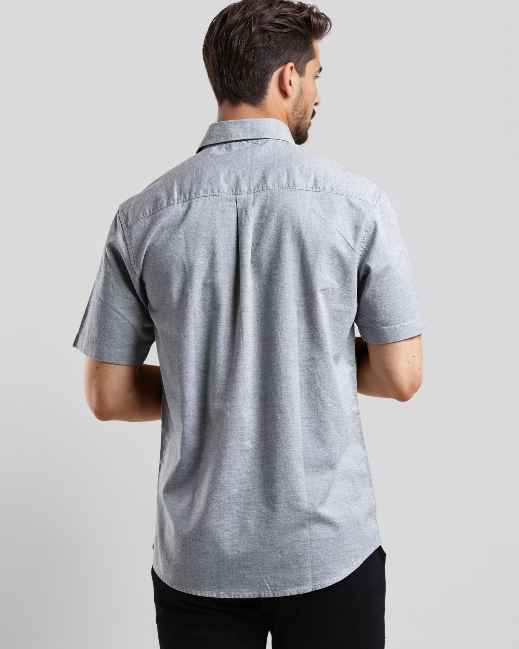 Man wearing a gray short-sleeve shirt on a light gray background