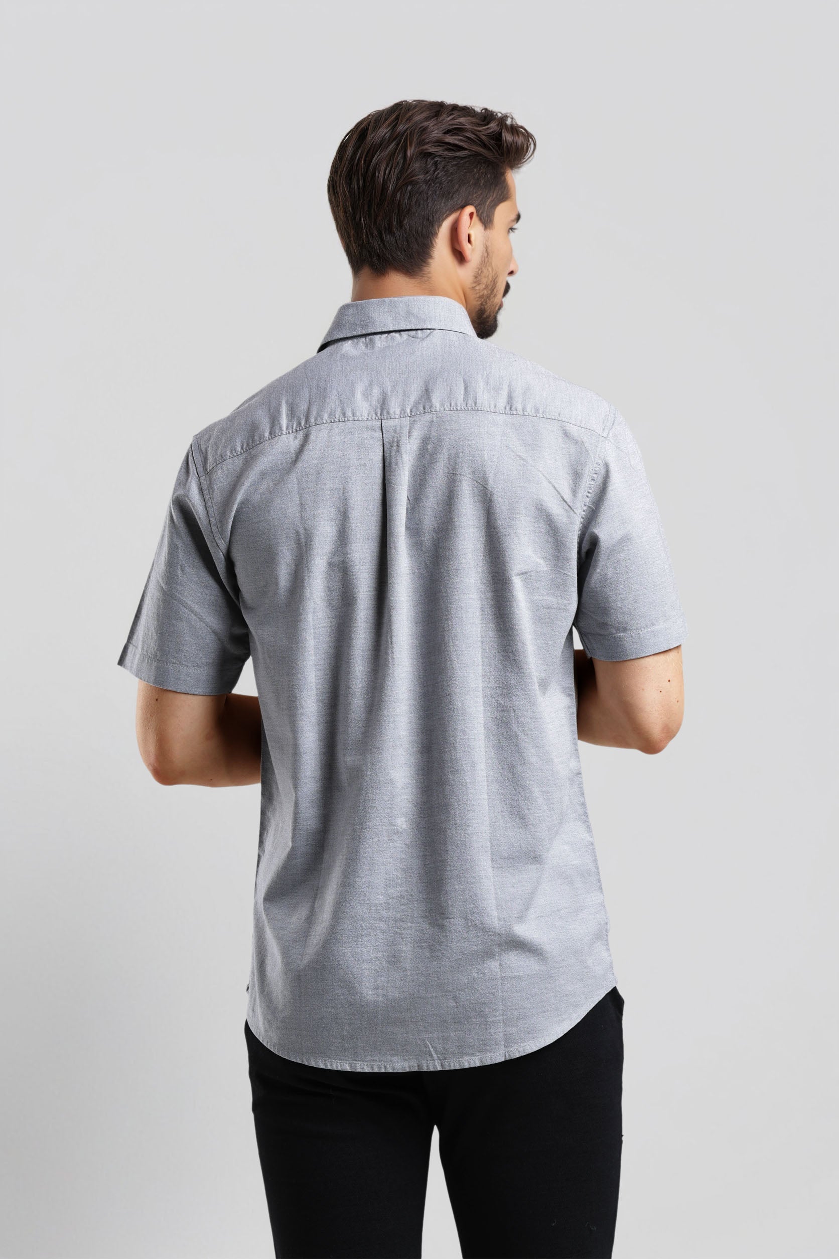 Man wearing a gray short-sleeve shirt on a light gray background