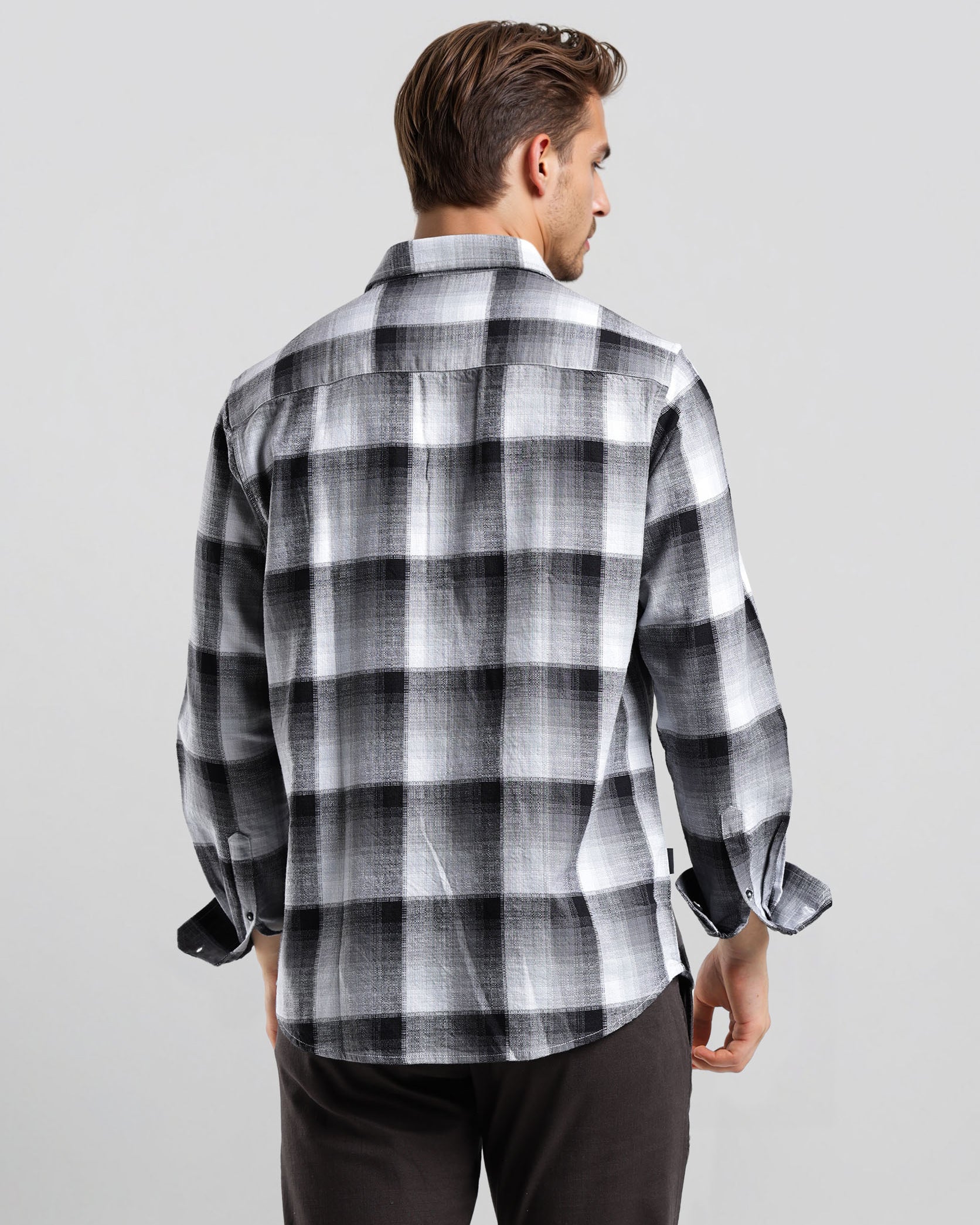 Man wearing a black and white checkered shirt against a gray background