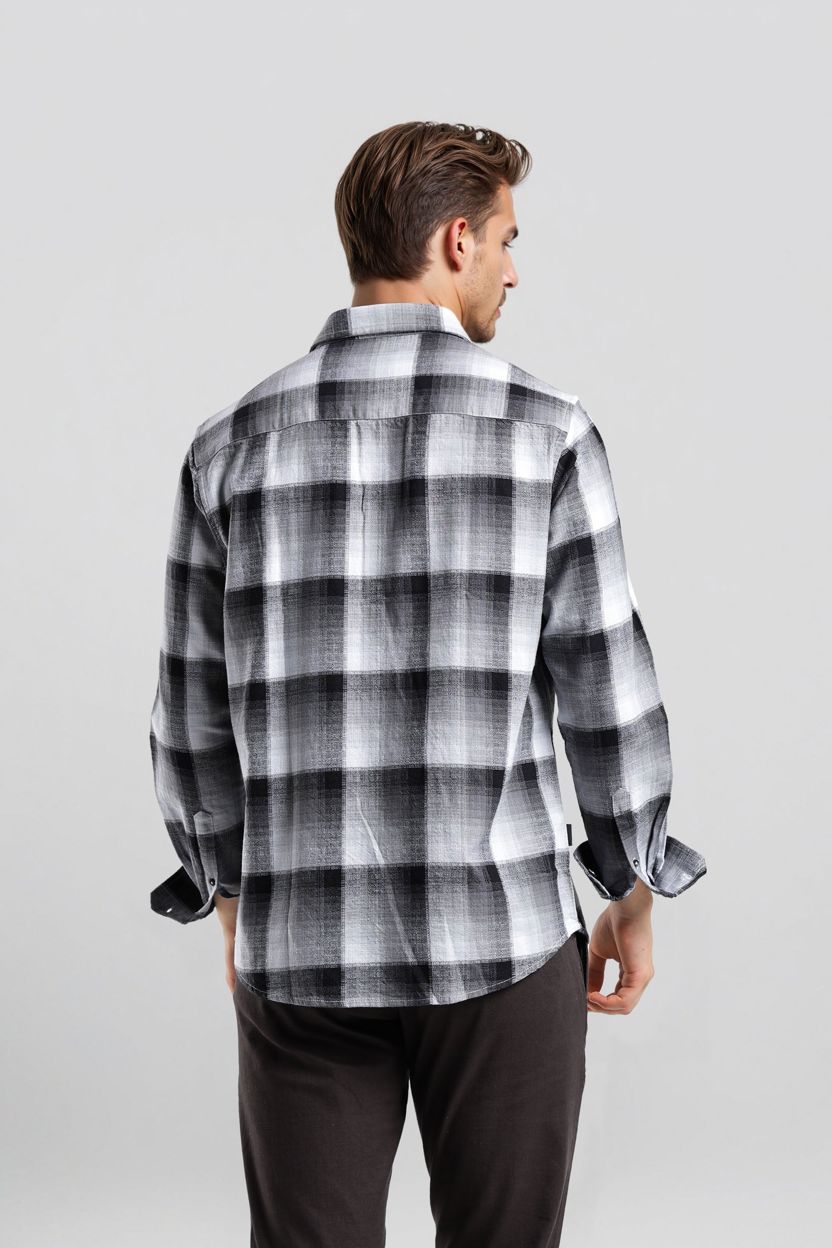 Man wearing a black and white checkered shirt against a gray background