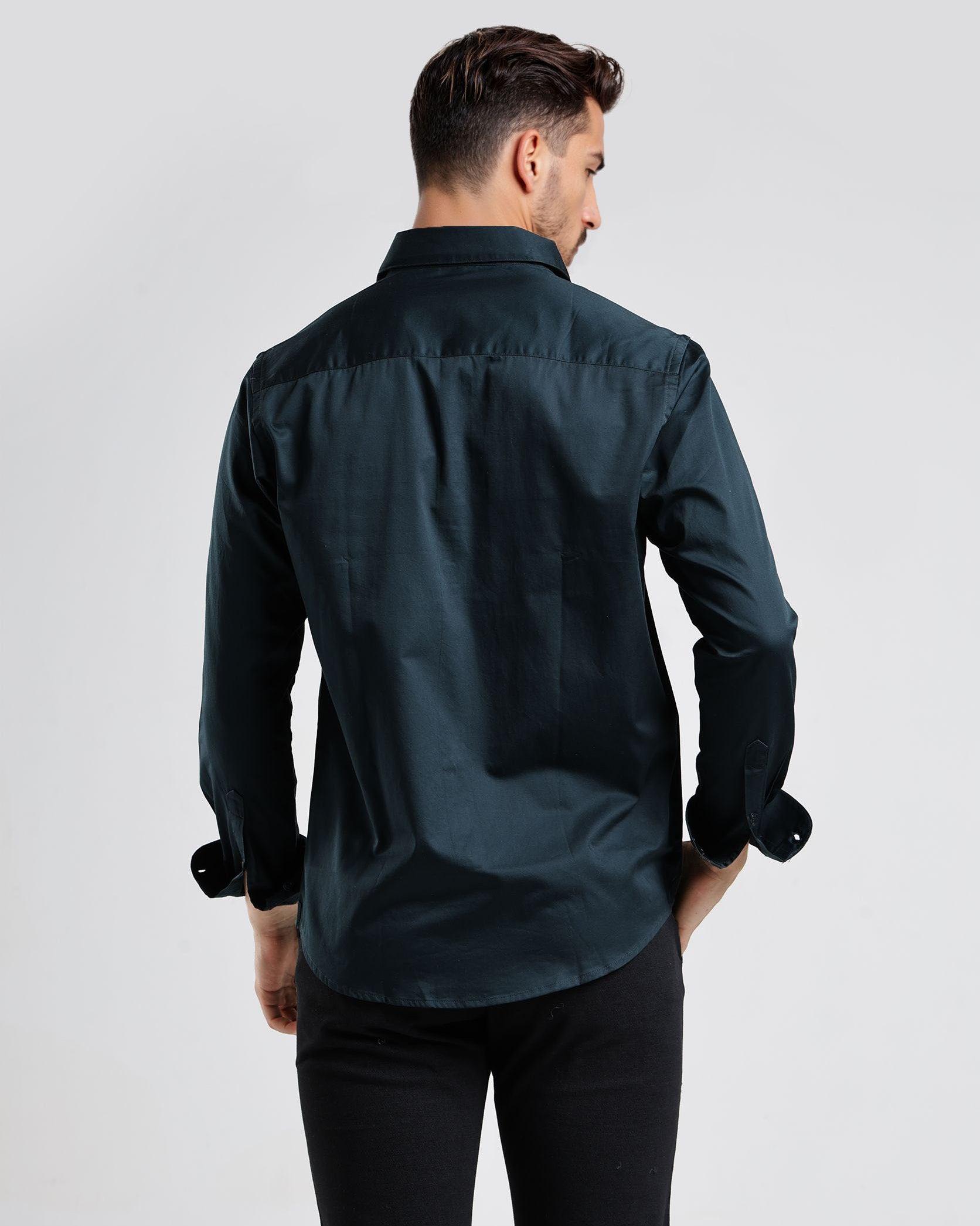 Man wearing a dark green shirt and black pants on a white background