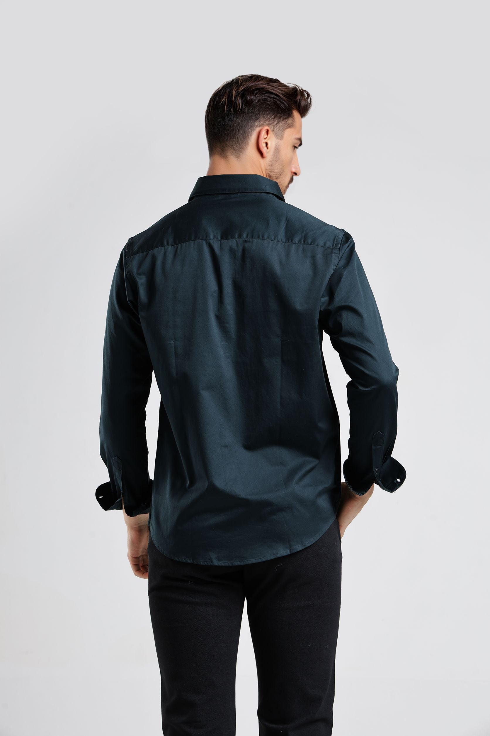 Man wearing a dark green shirt and black pants on a white background