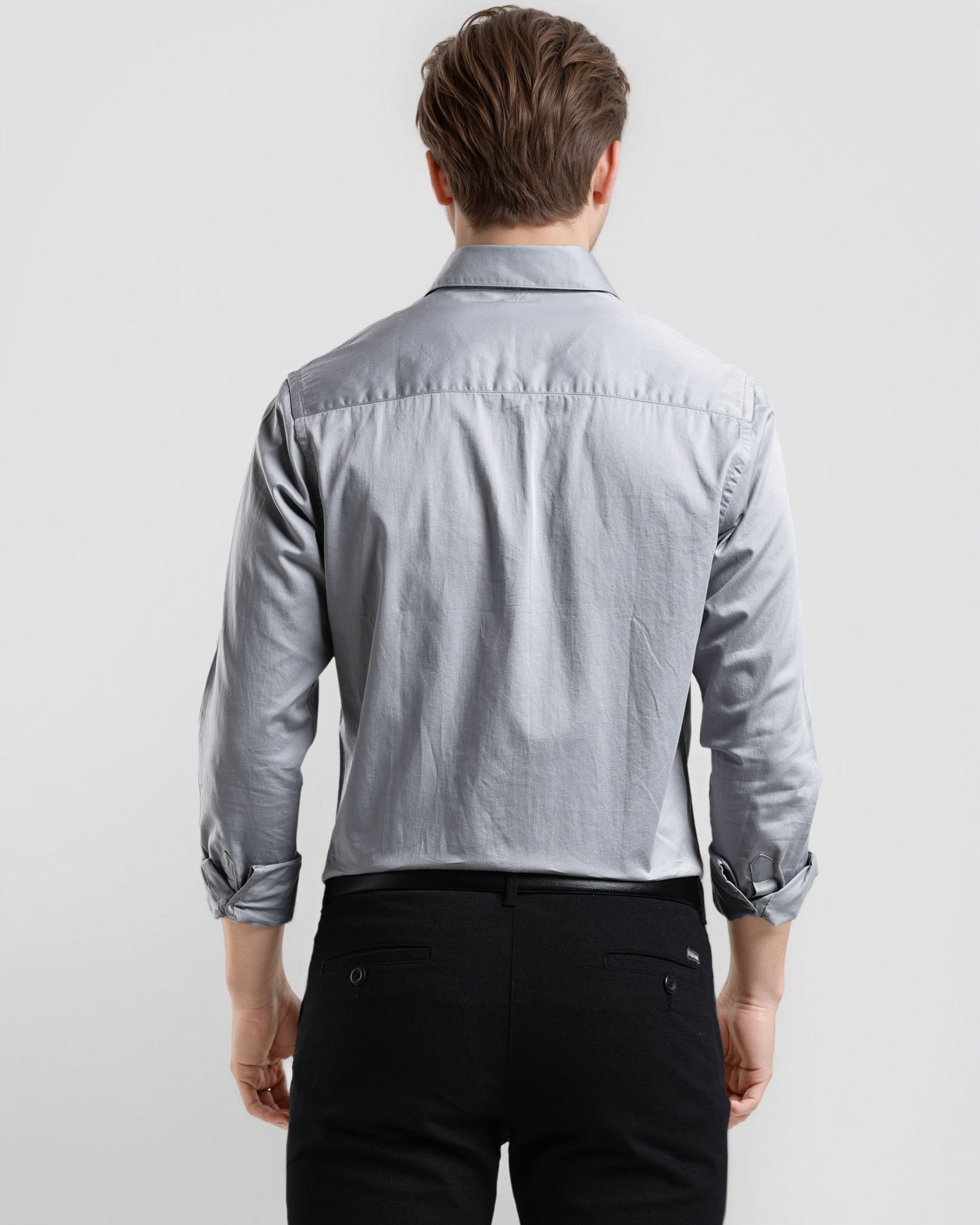 Man wearing a light blue denim shirt and black pants on a white background