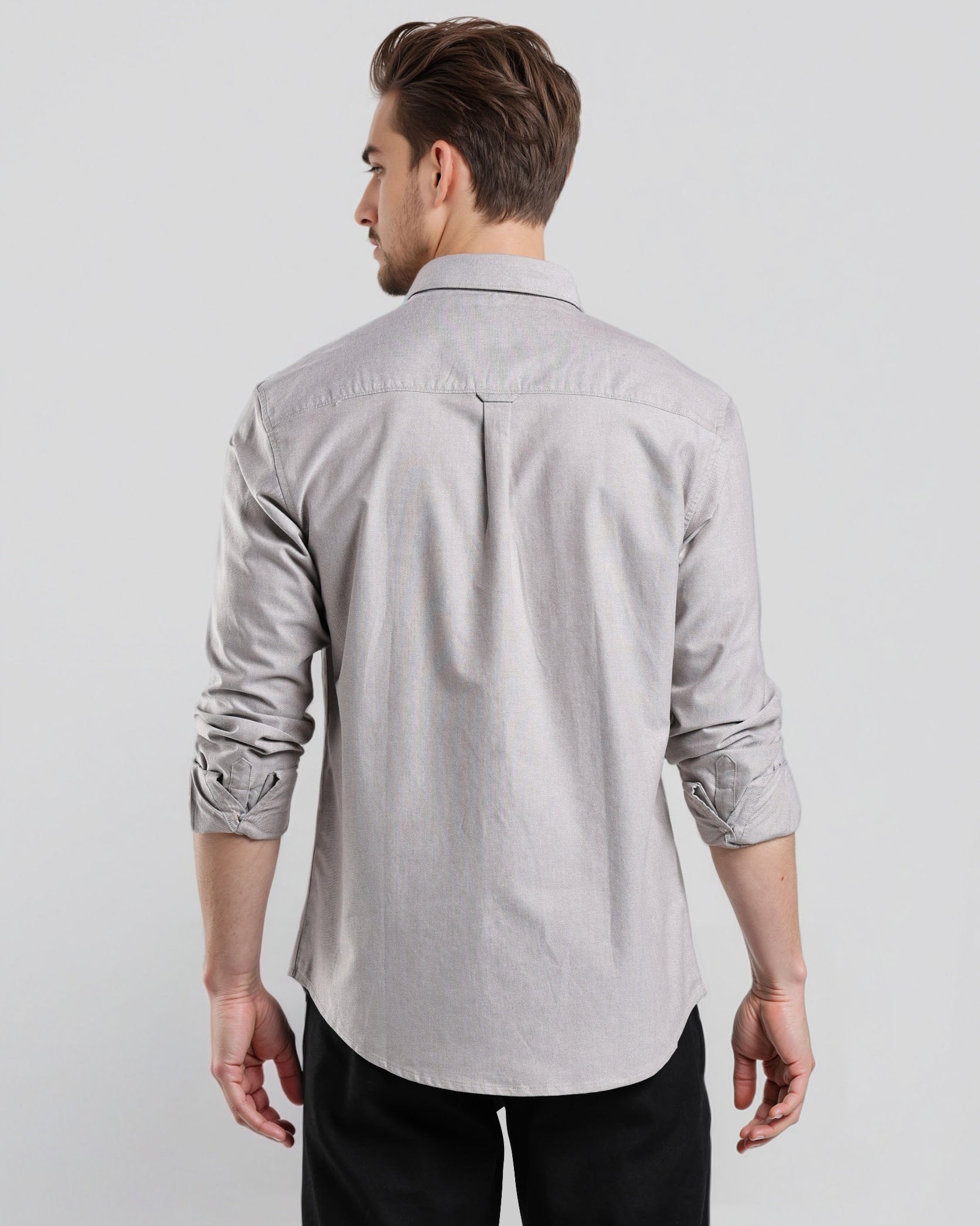 Man wearing a light gray button-up shirt and black pants on a white background