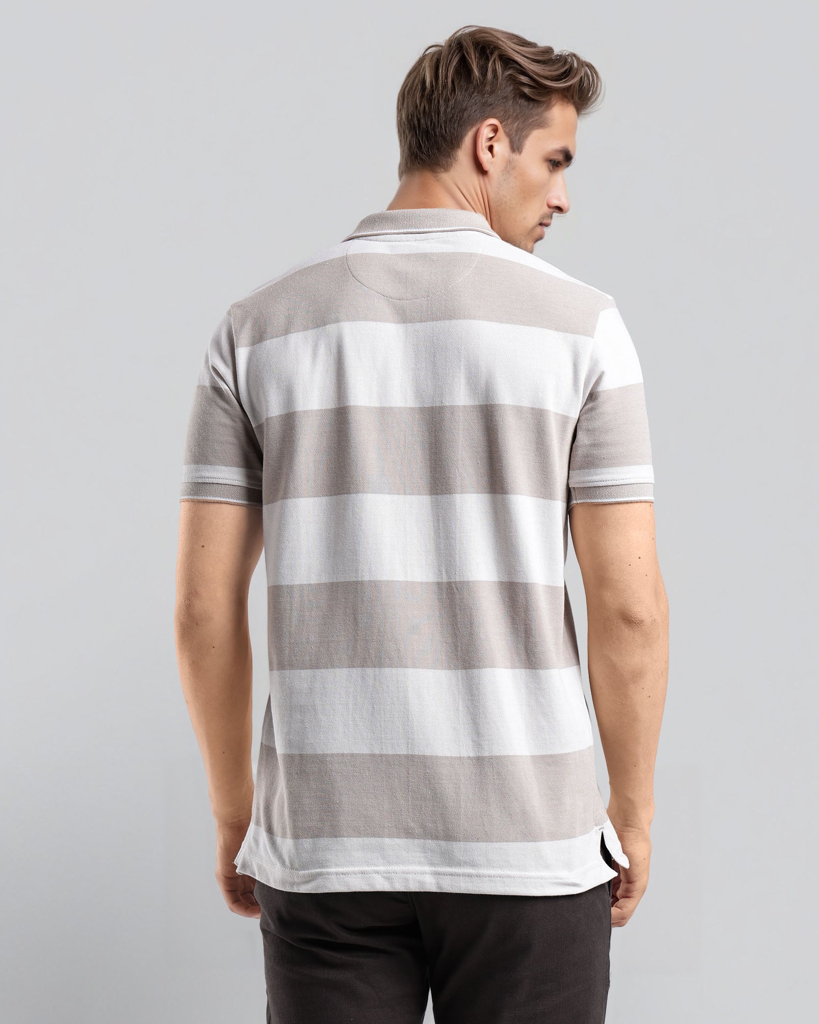 Man wearing a gray and white striped polo shirt on a light gray background