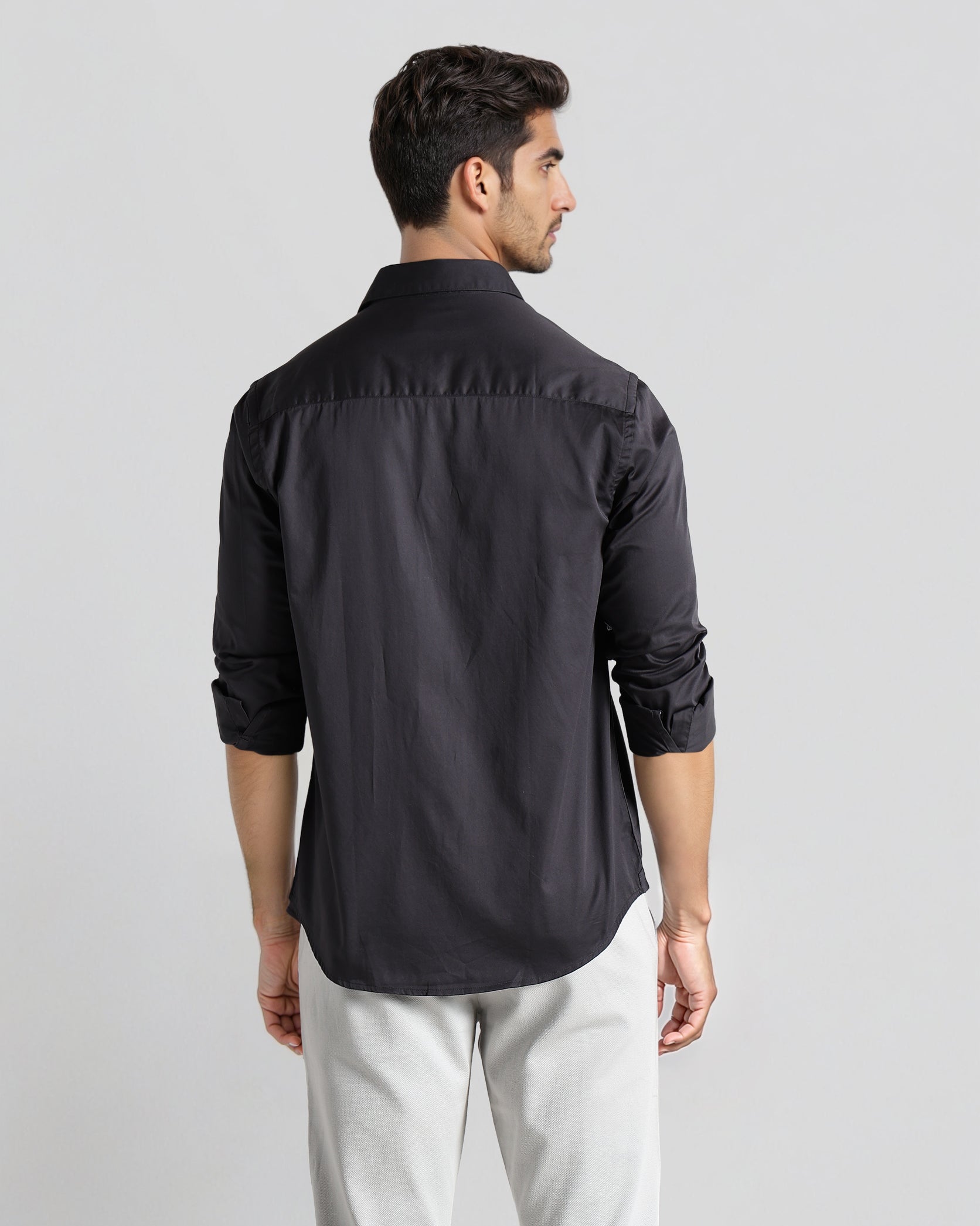 Man wearing a black shirt and light gray pants on a white background