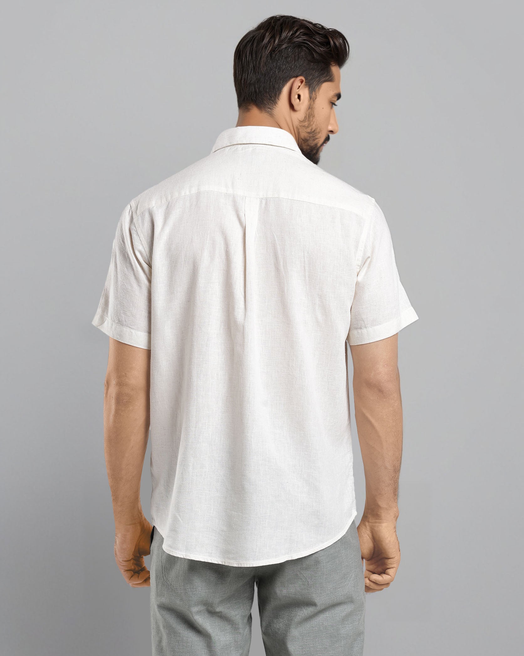 Man wearing a white shirt and gray pants on a gray background