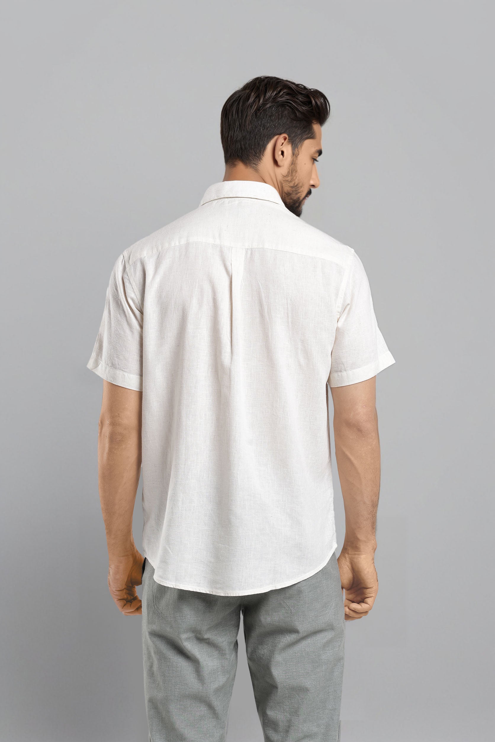 Man wearing a white shirt and gray pants on a gray background