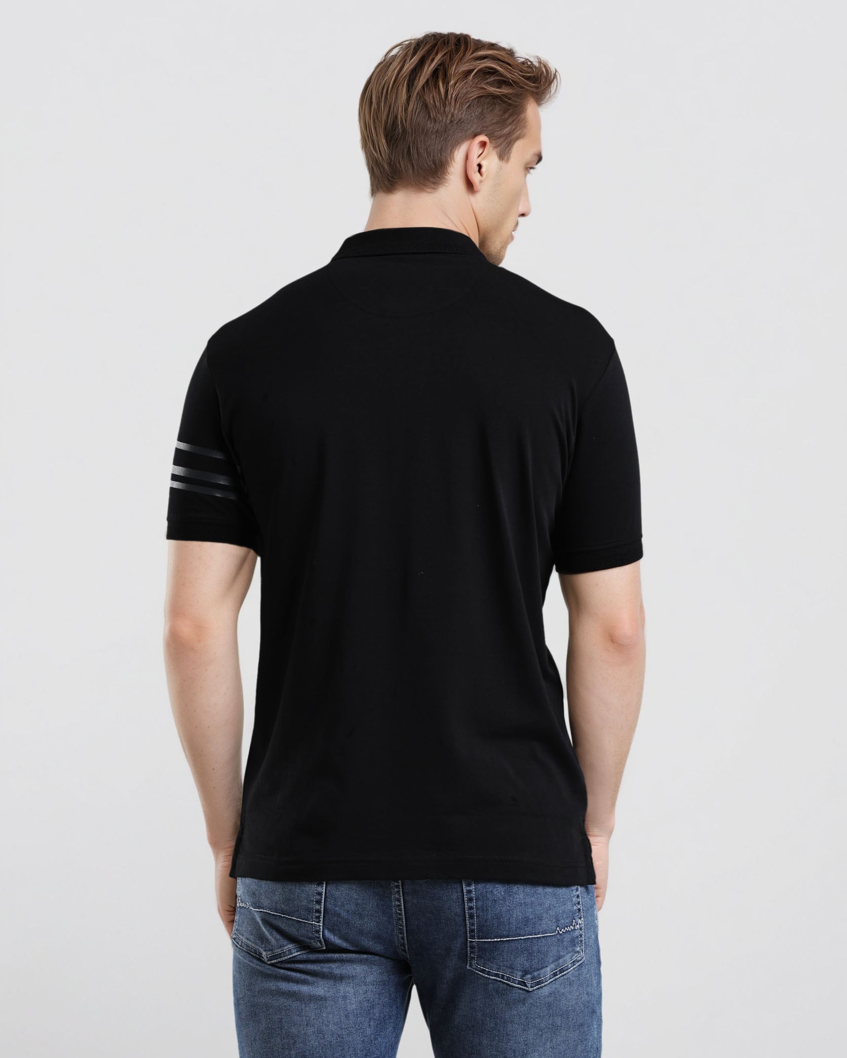 Man wearing a black polo shirt with a white stripe on a light gray background