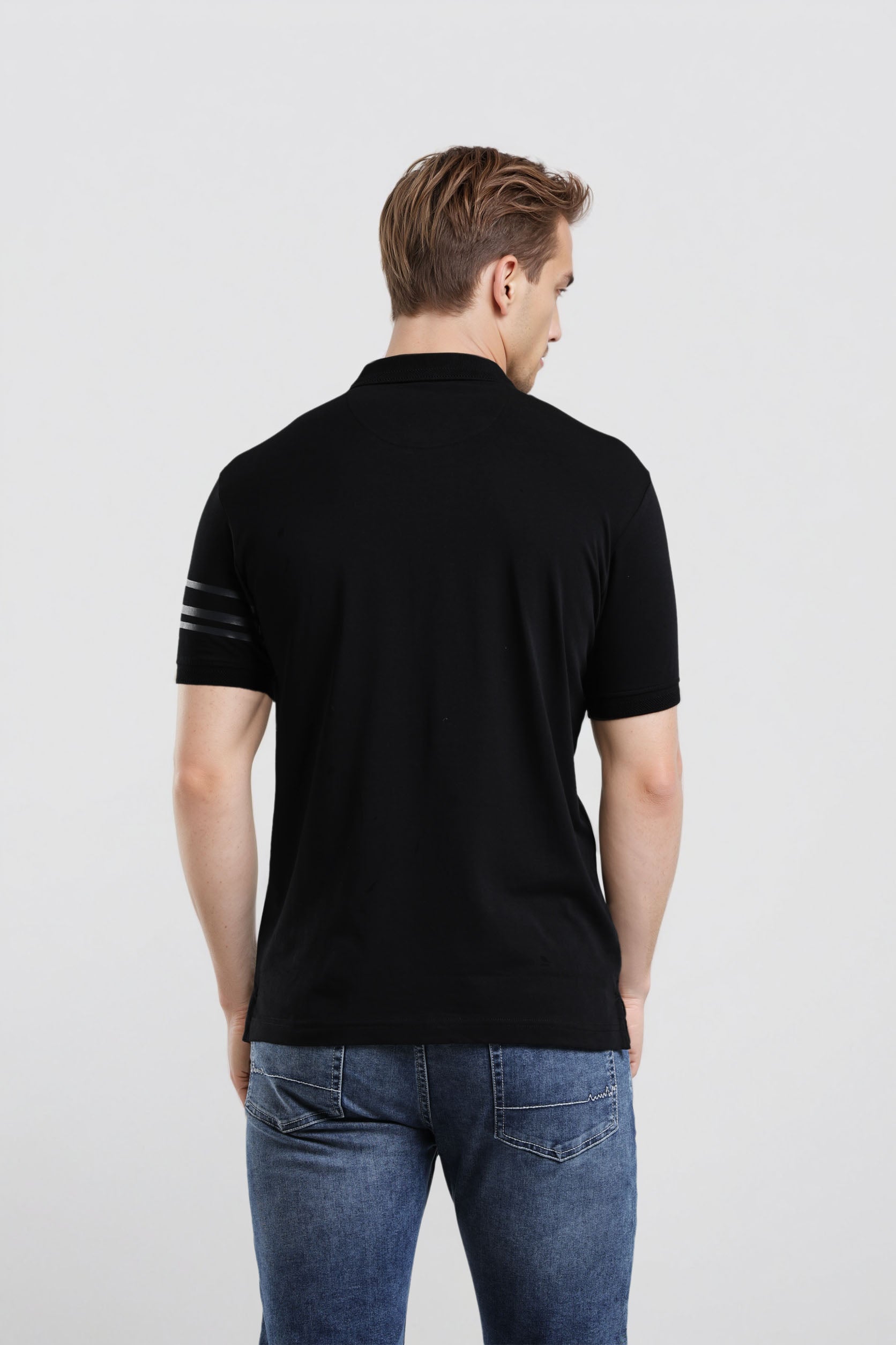 Man wearing a black polo shirt with a white stripe on a light gray background