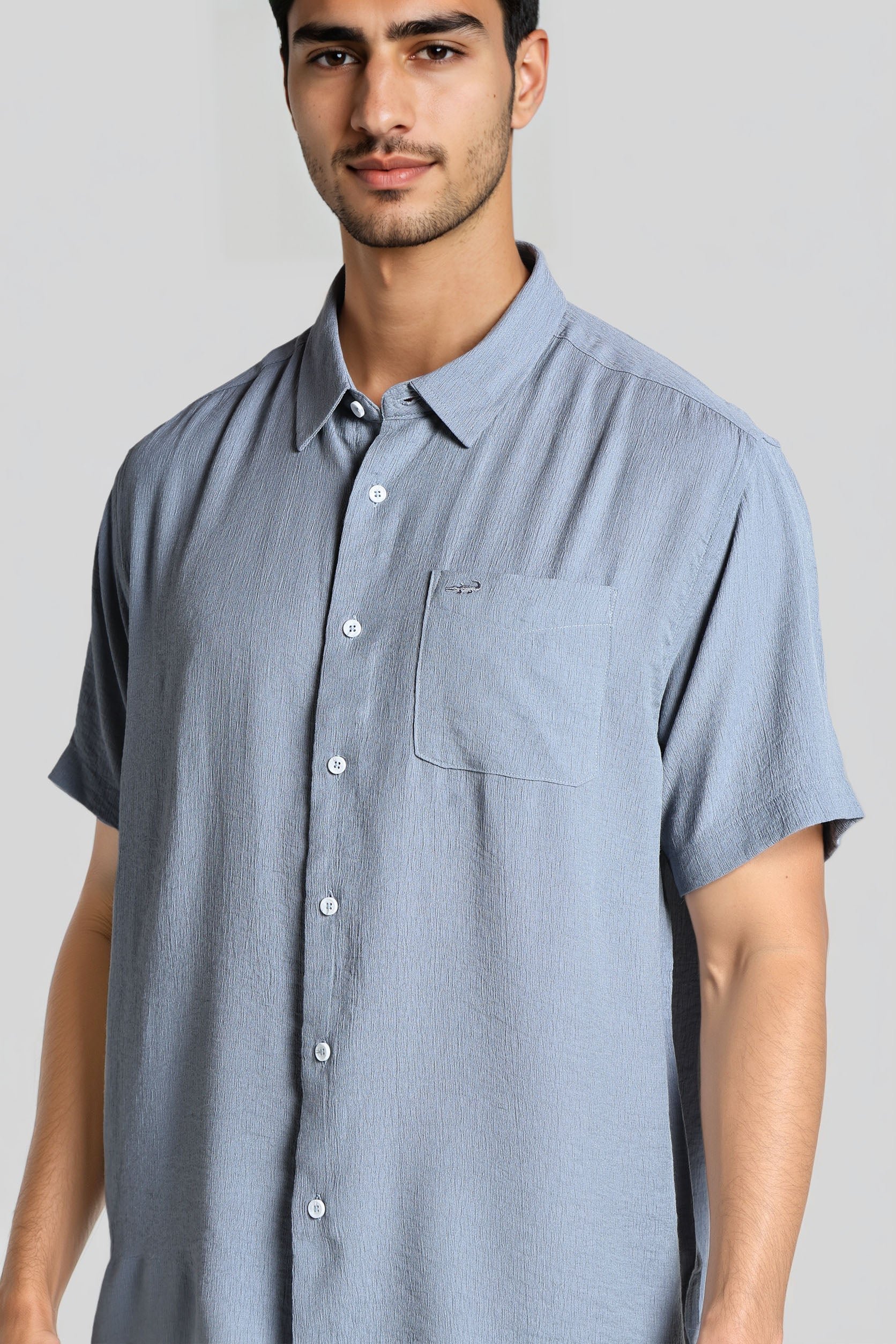 Man wearing a light blue short-sleeve shirt against a plain background