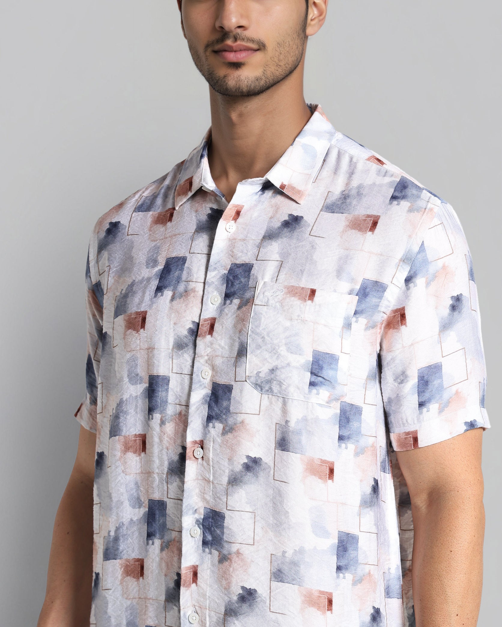 Man wearing a short-sleeve shirt with a geometric pattern on a gray background