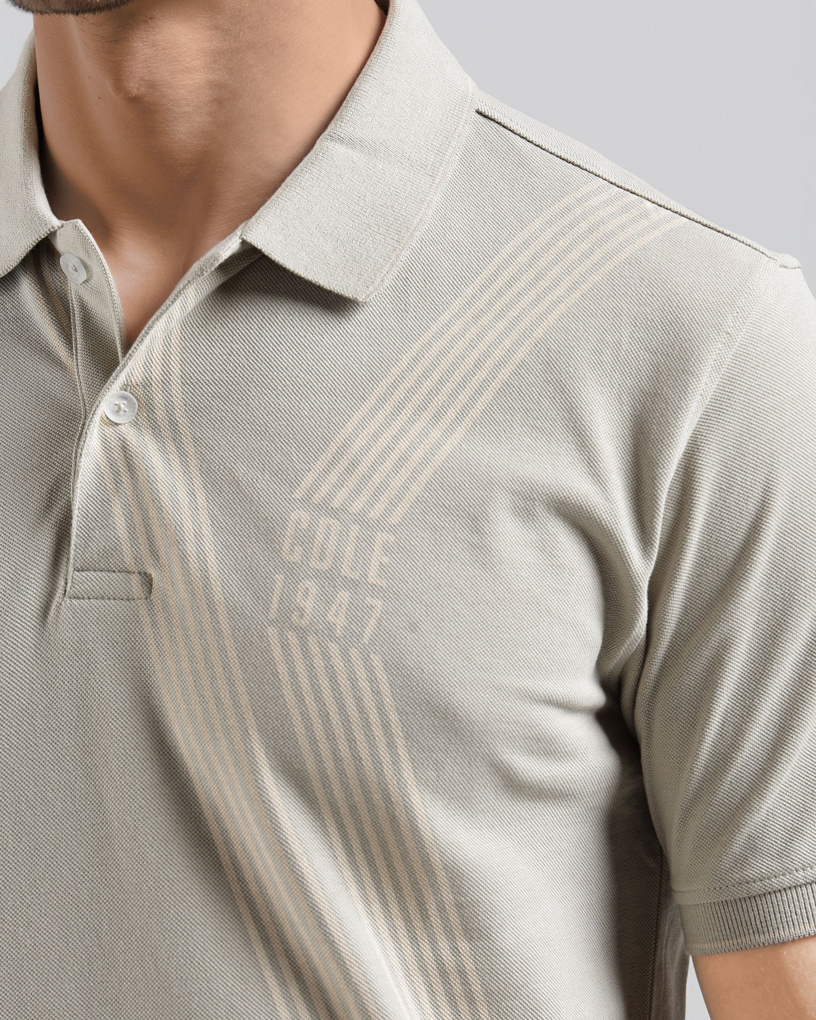 Beige polo shirt with 'Cole 1947' branding on a plain background