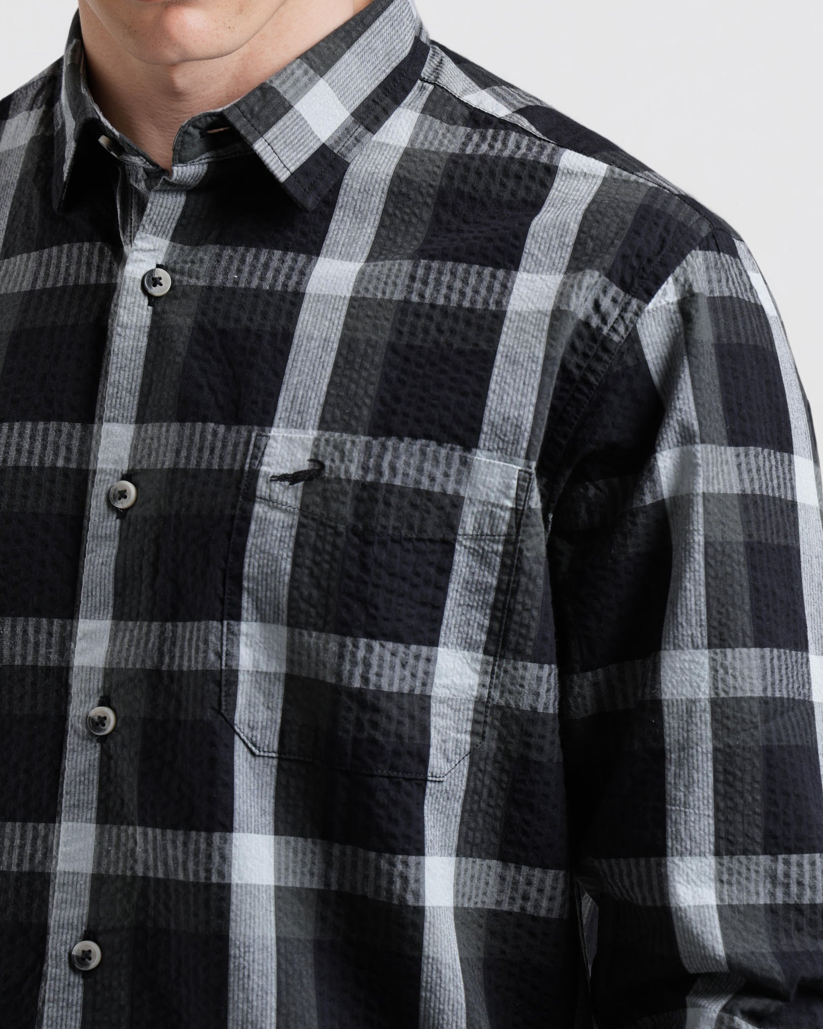 Person wearing a black and gray plaid shirt against a white background