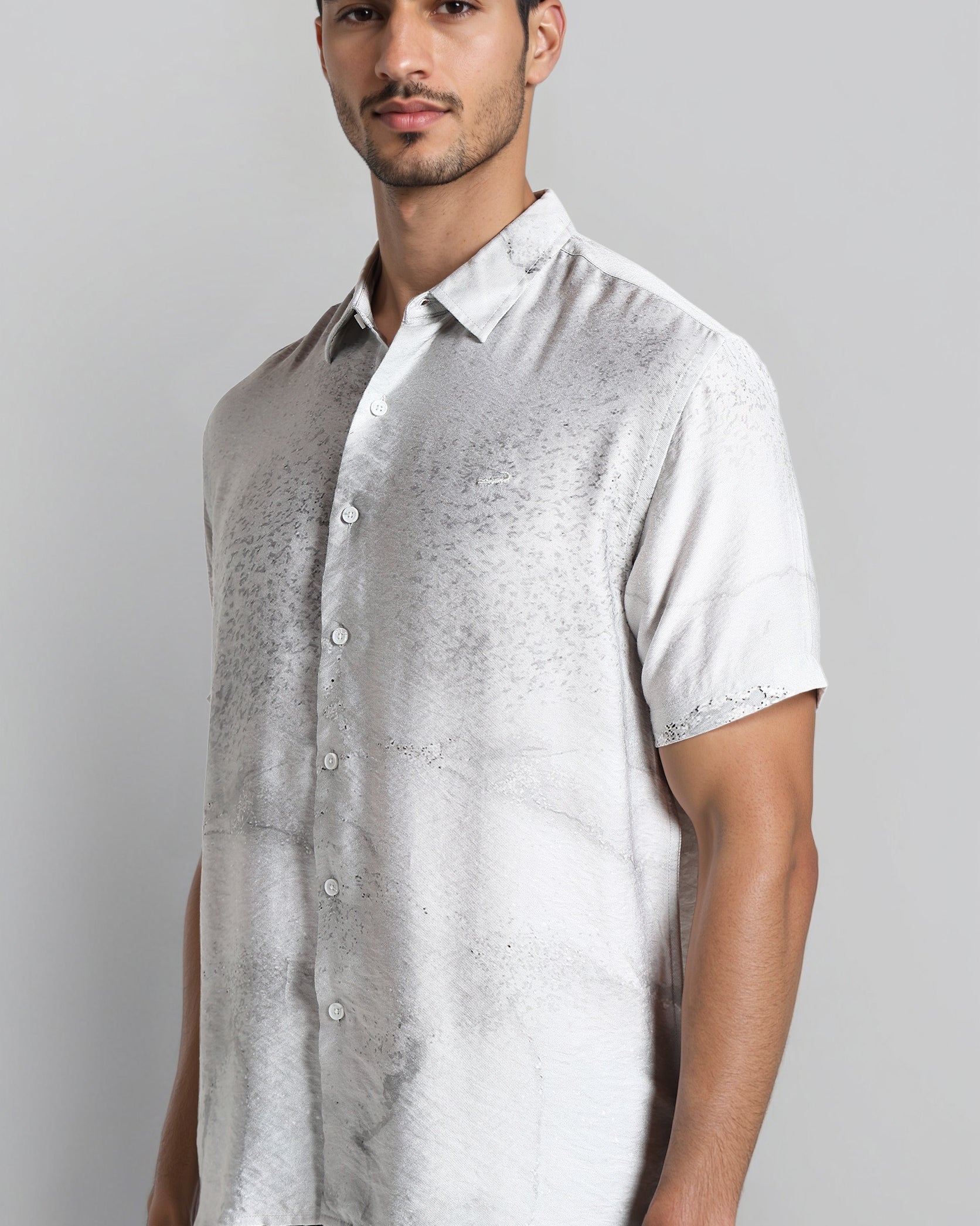 Man wearing a light gray patterned shirt against a plain background