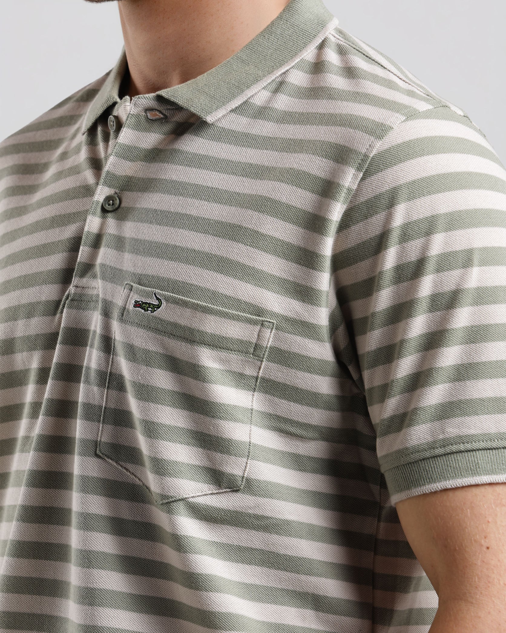 Man wearing a striped polo shirt with a neutral background