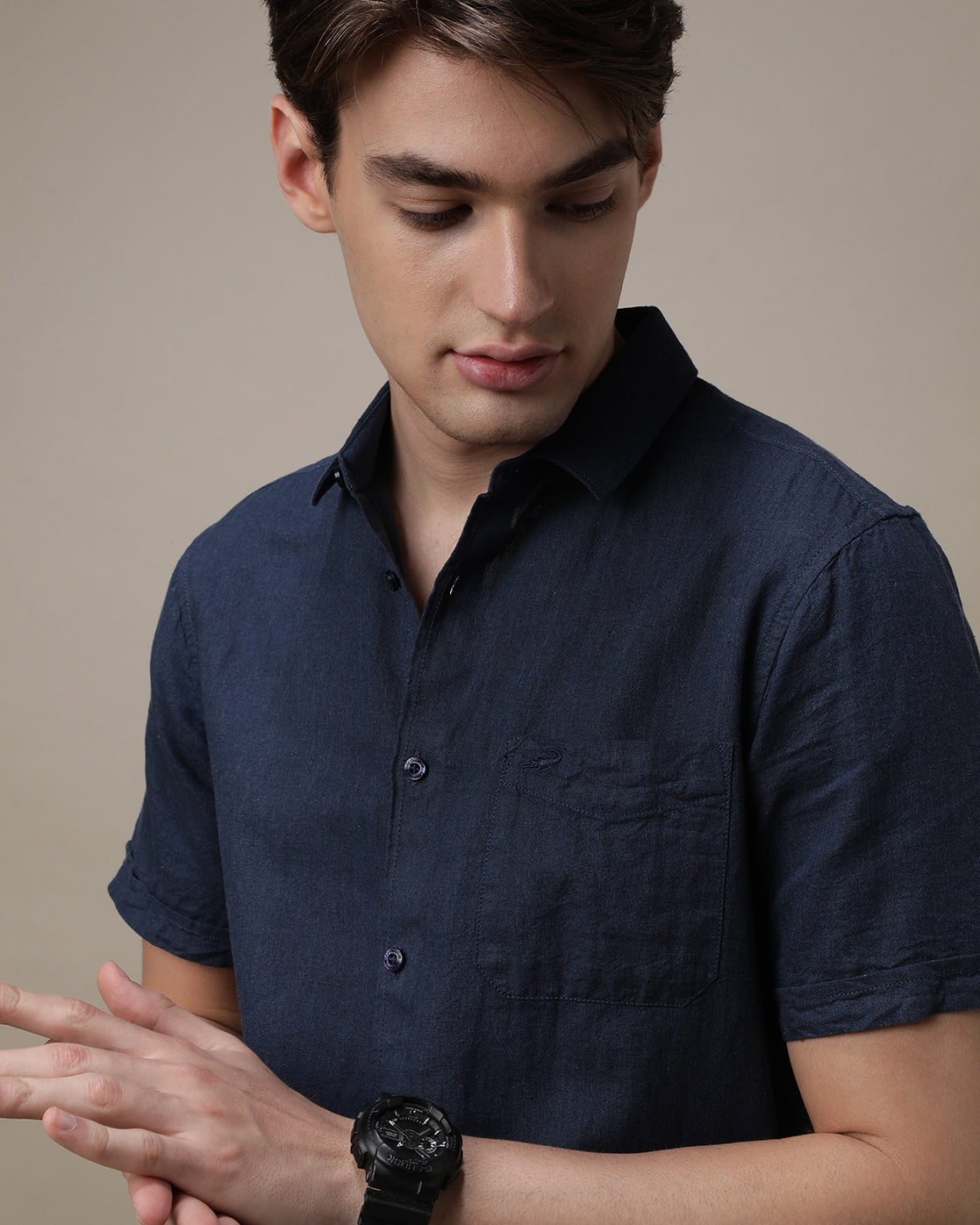 Man wearing a navy navy solid half sleeve linen shirt on a light gray background