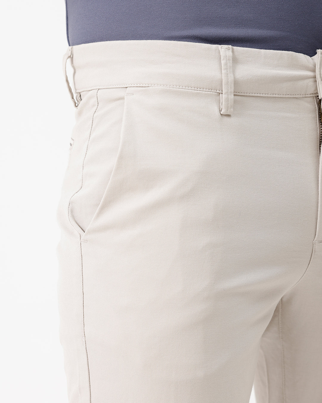 A person wearing light beige chino pants, a dark blue-gray t-shirt, and brown suede moccasin shoes, standing against a plain white studio background.
