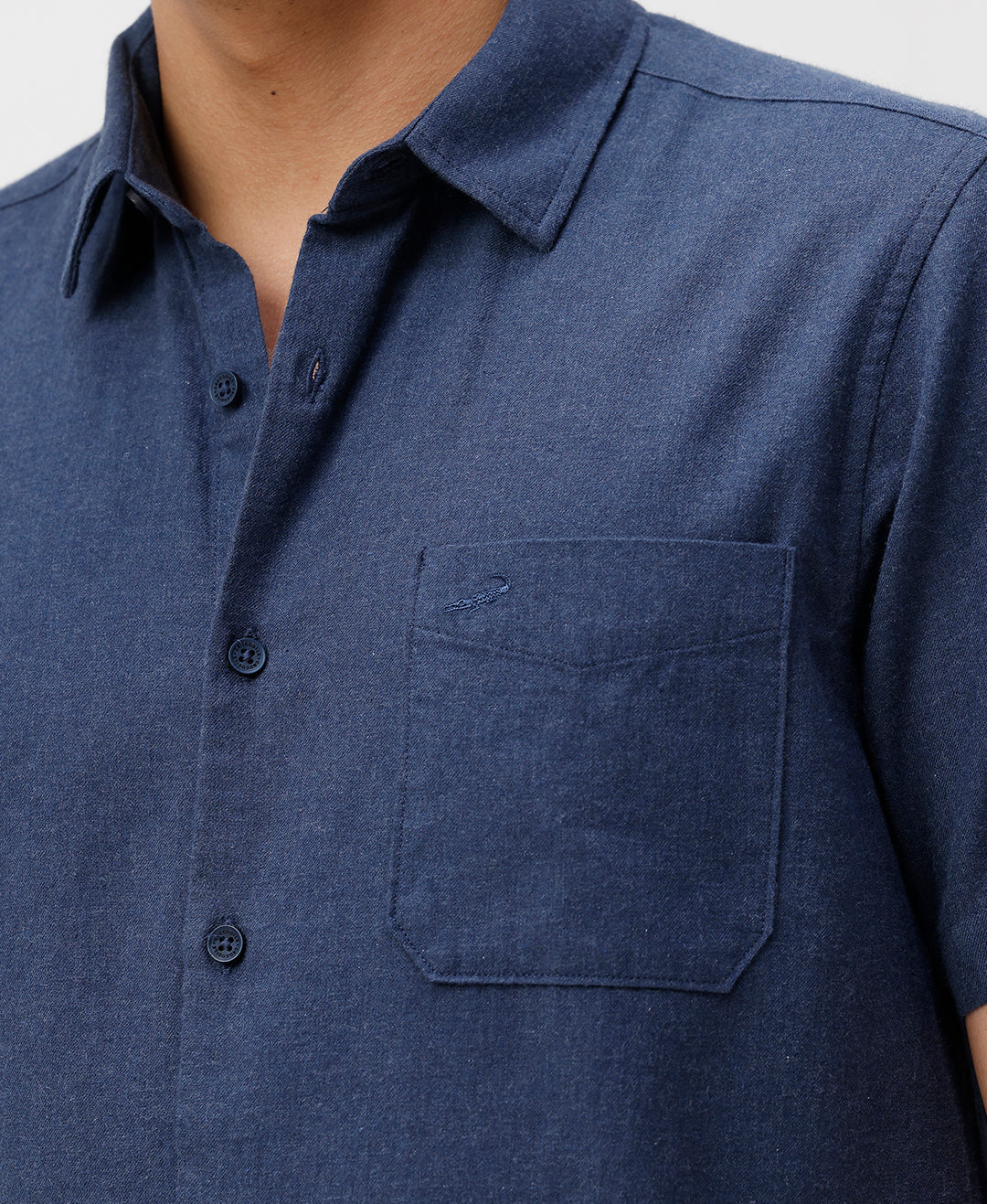 Man wearing a blue melange shirt solid blue on a light gray background