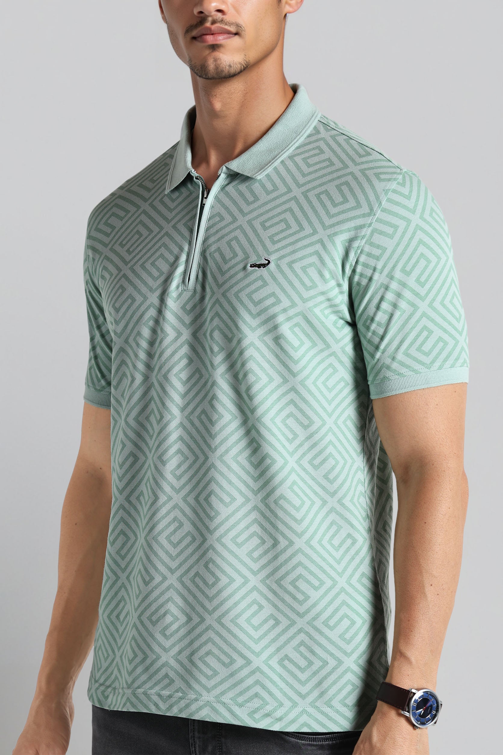 Man wearing a light green patterned polo shirt on a gray background
