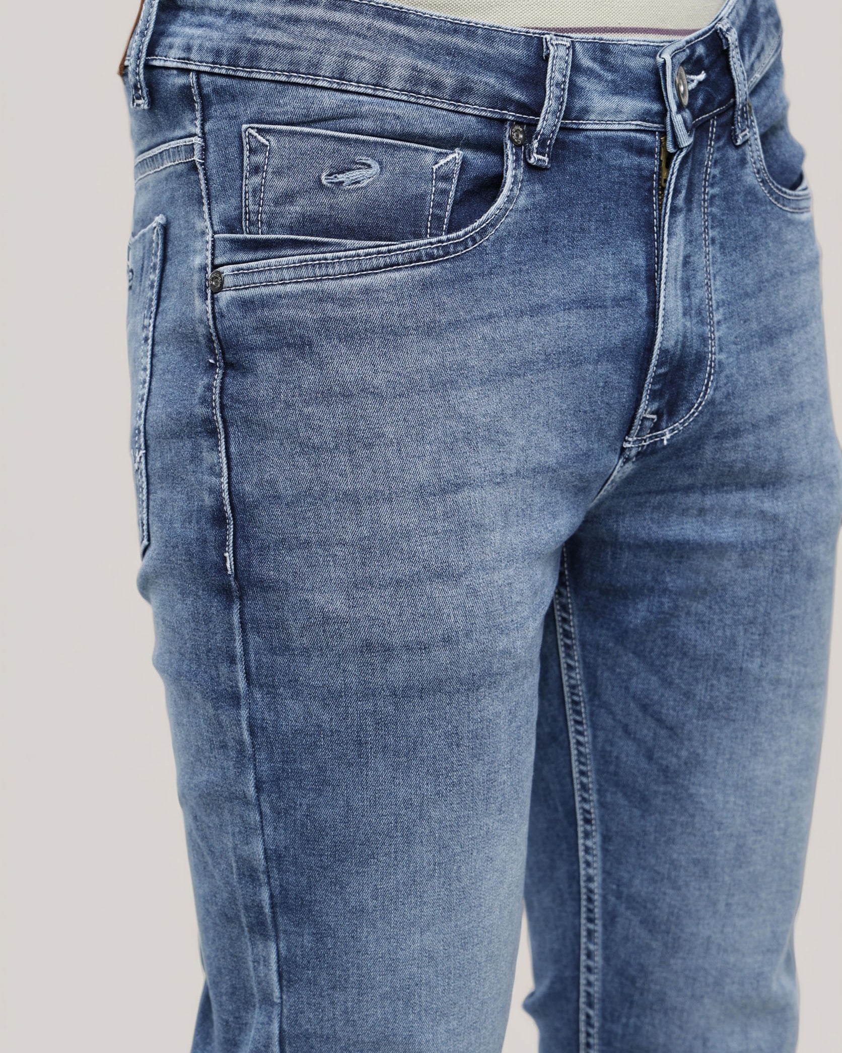 Blue jeans worn by a person on a plain background